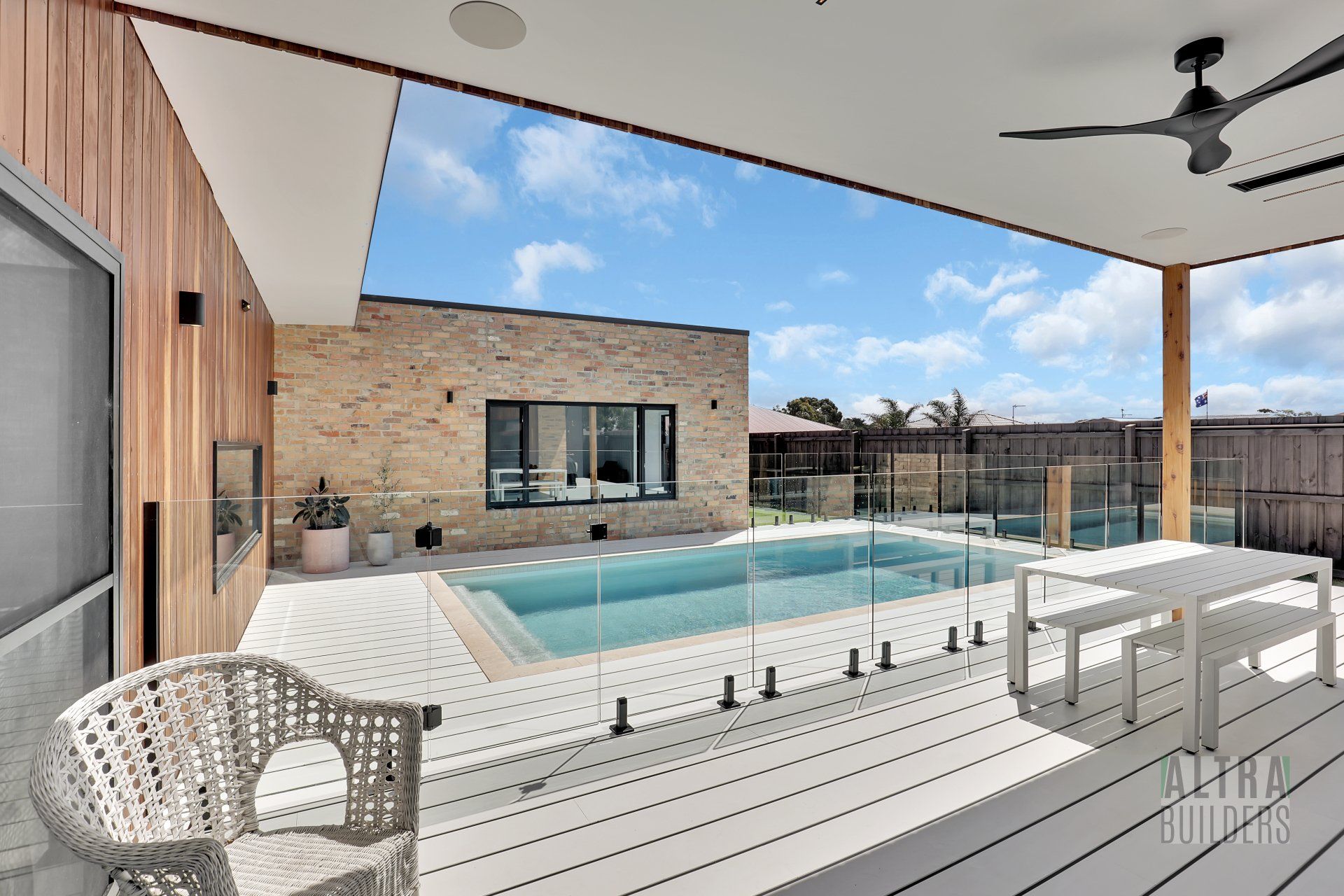 A large swimming pool is surrounded by a white deck