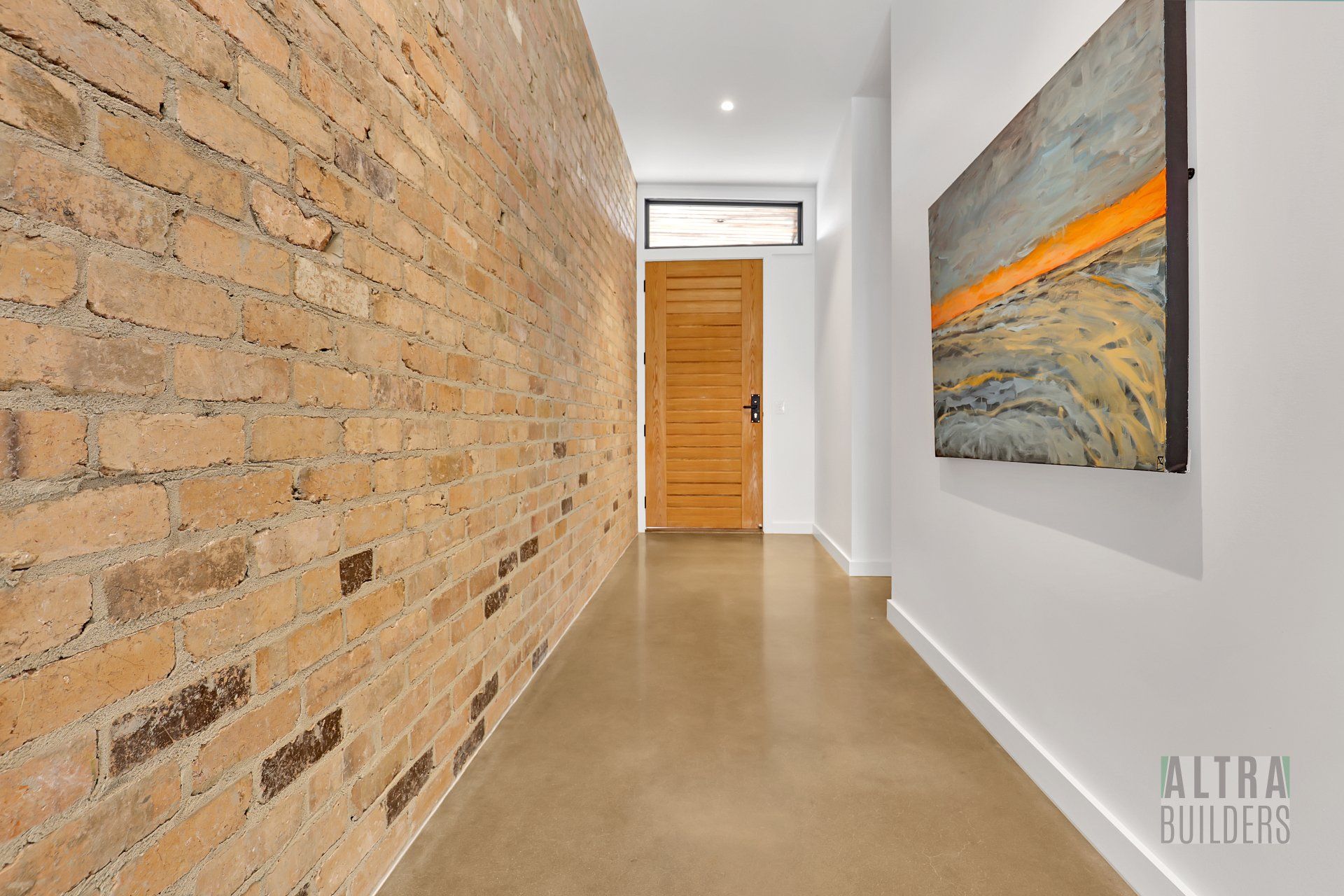 A long hallway with a brick wall and a painting on the wall