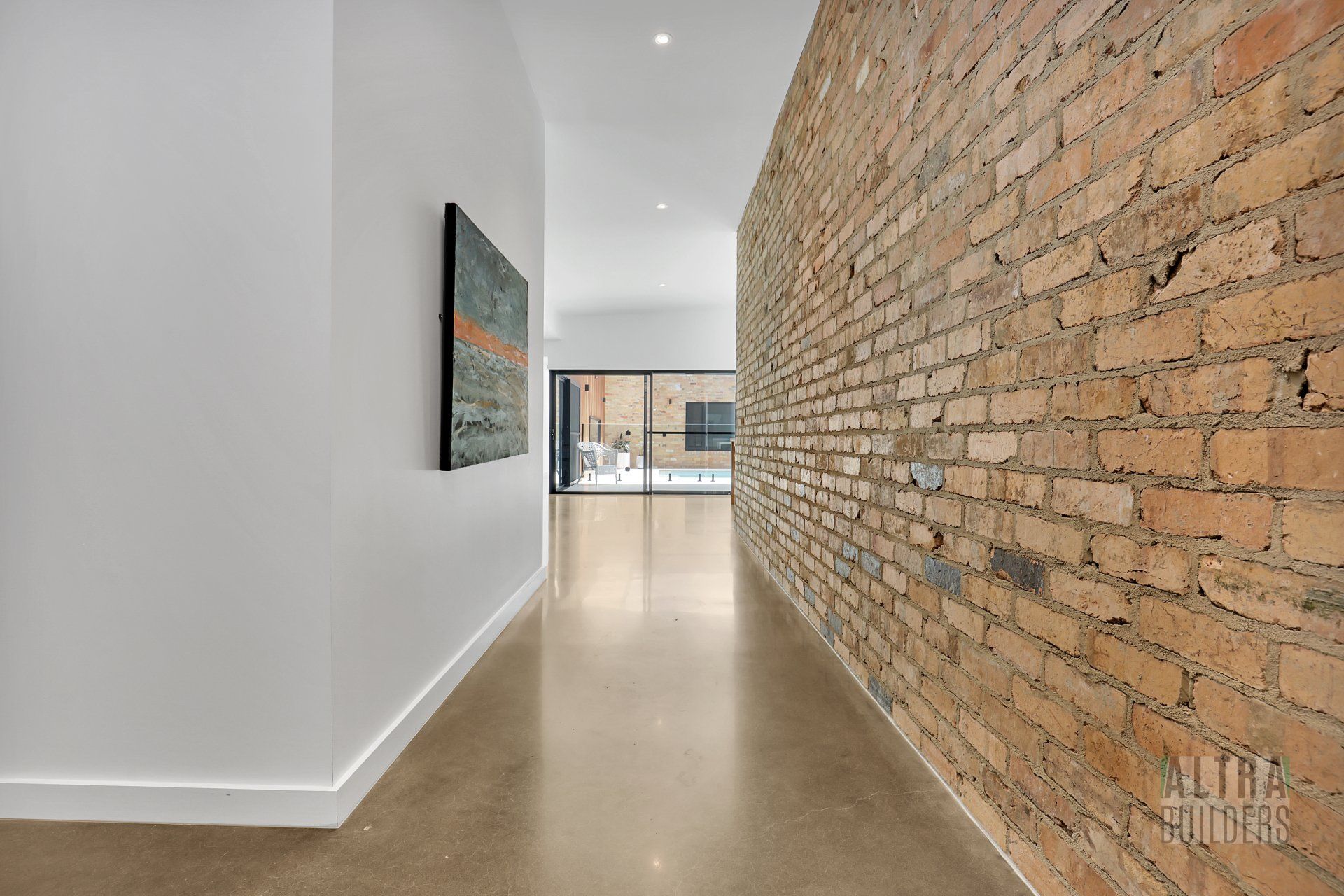 A long hallway with a brick wall and a painting on the wall.