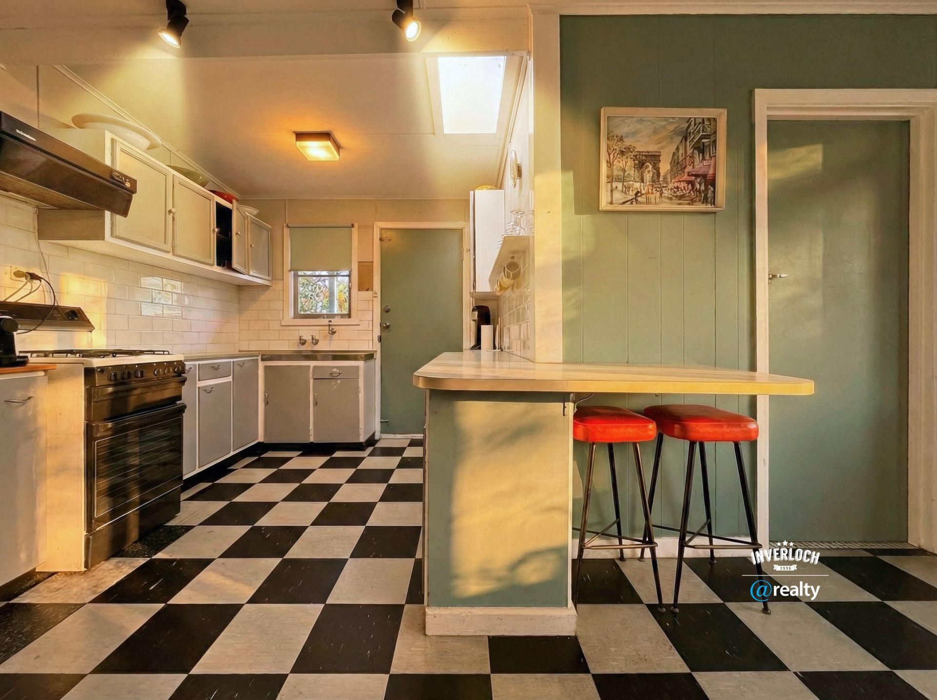 A vintage-style kitchen with a black-and-white checkered floor, pale green walls, and a breakfast bar with red stools.