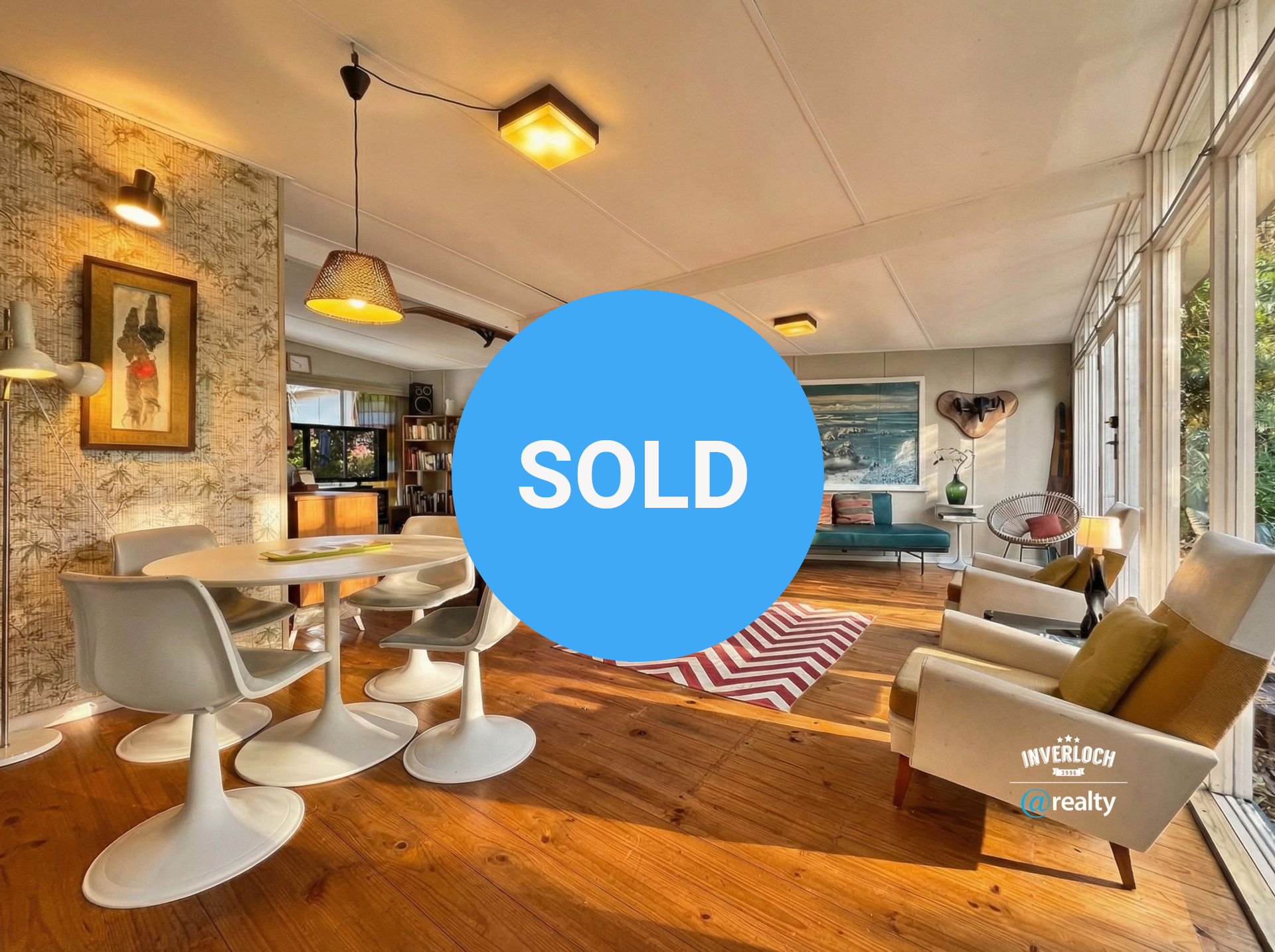 Spacious living room with wooden floors, modern furniture, and a large window overlooking trees.