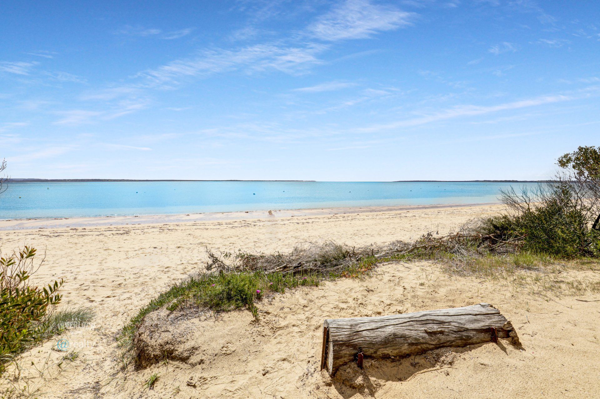A log is sitting on a sandy beach next to the ocean.