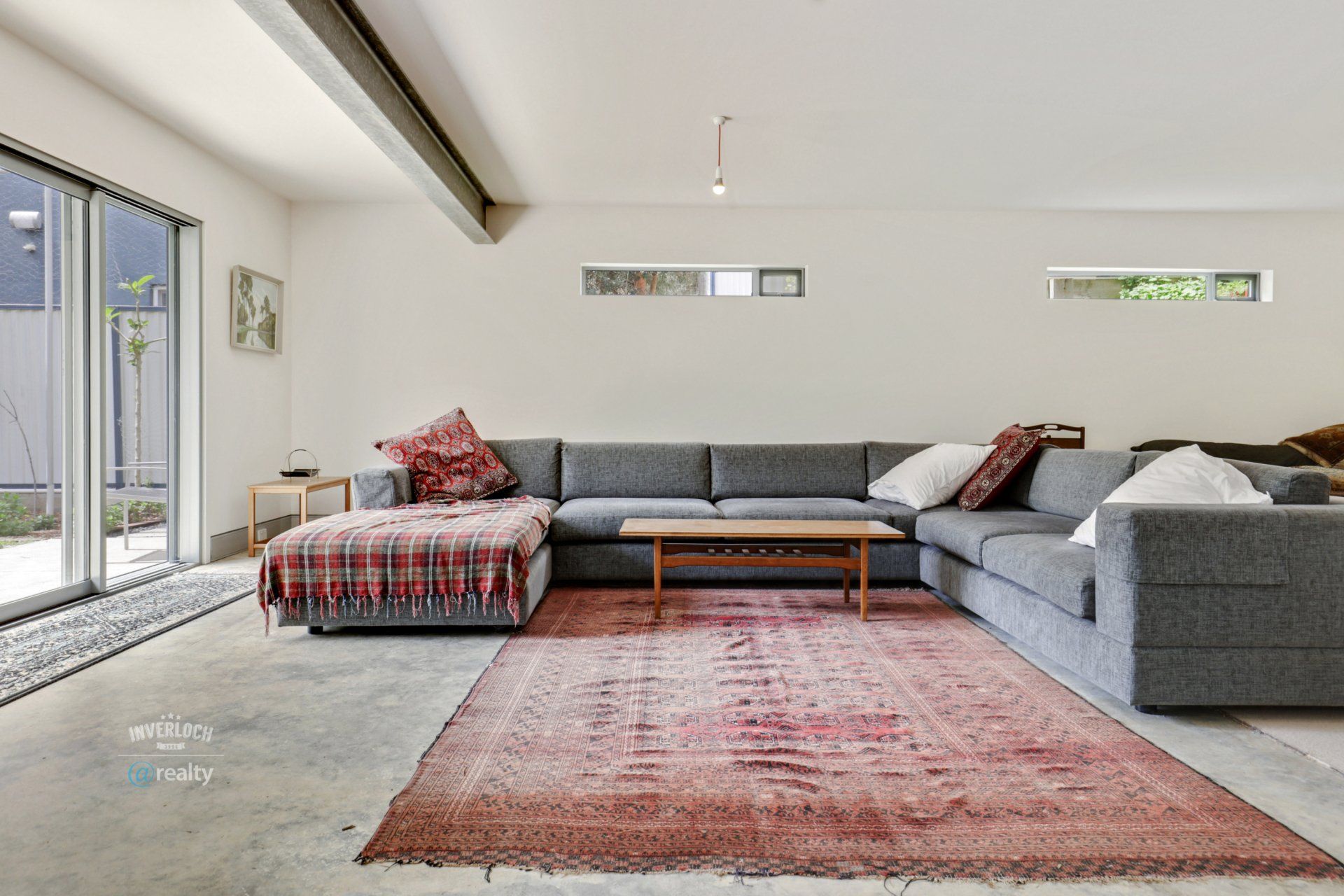 A living room with a large sectional couch and a rug.