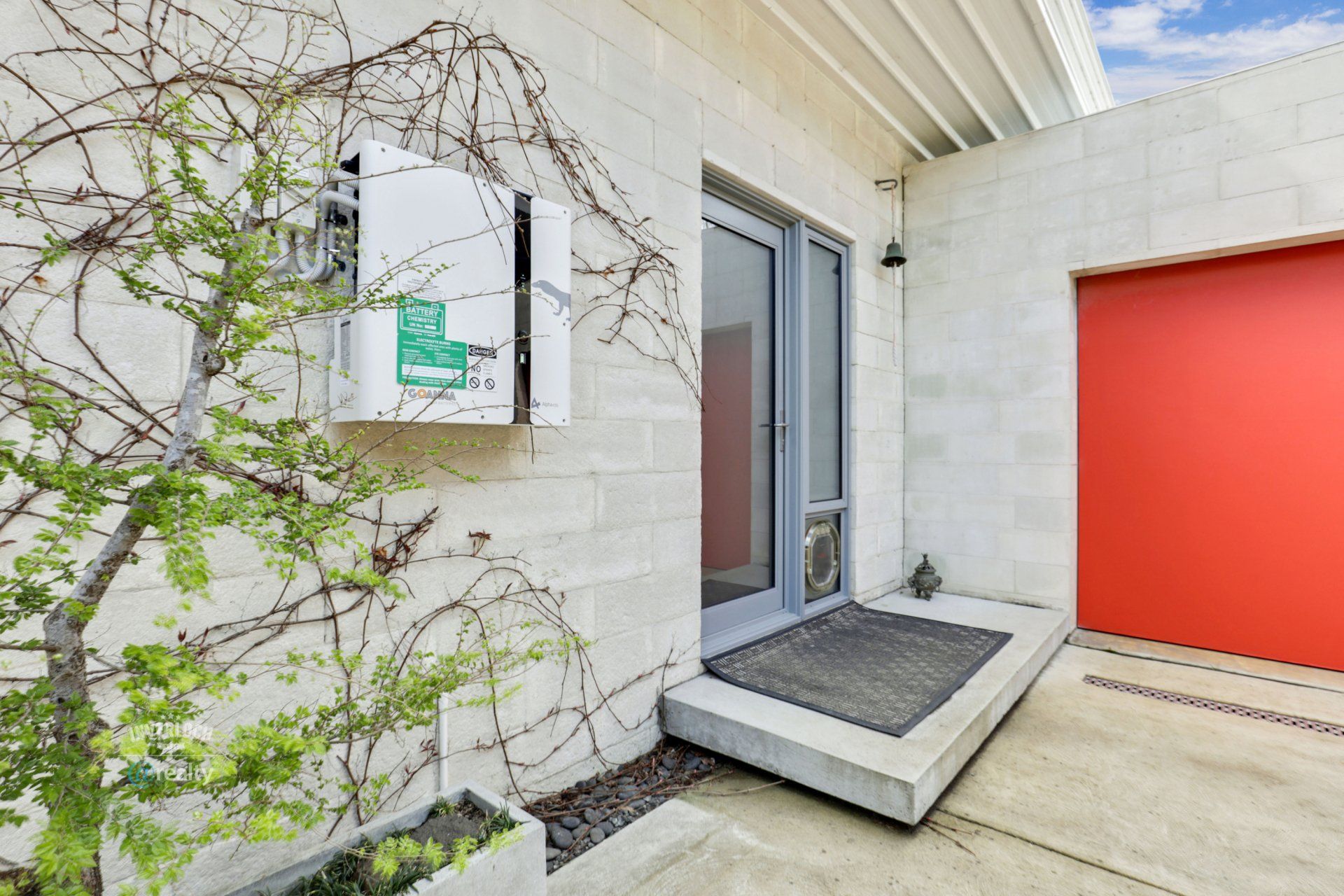 A white brick house with a red garage door and a white mailbox.