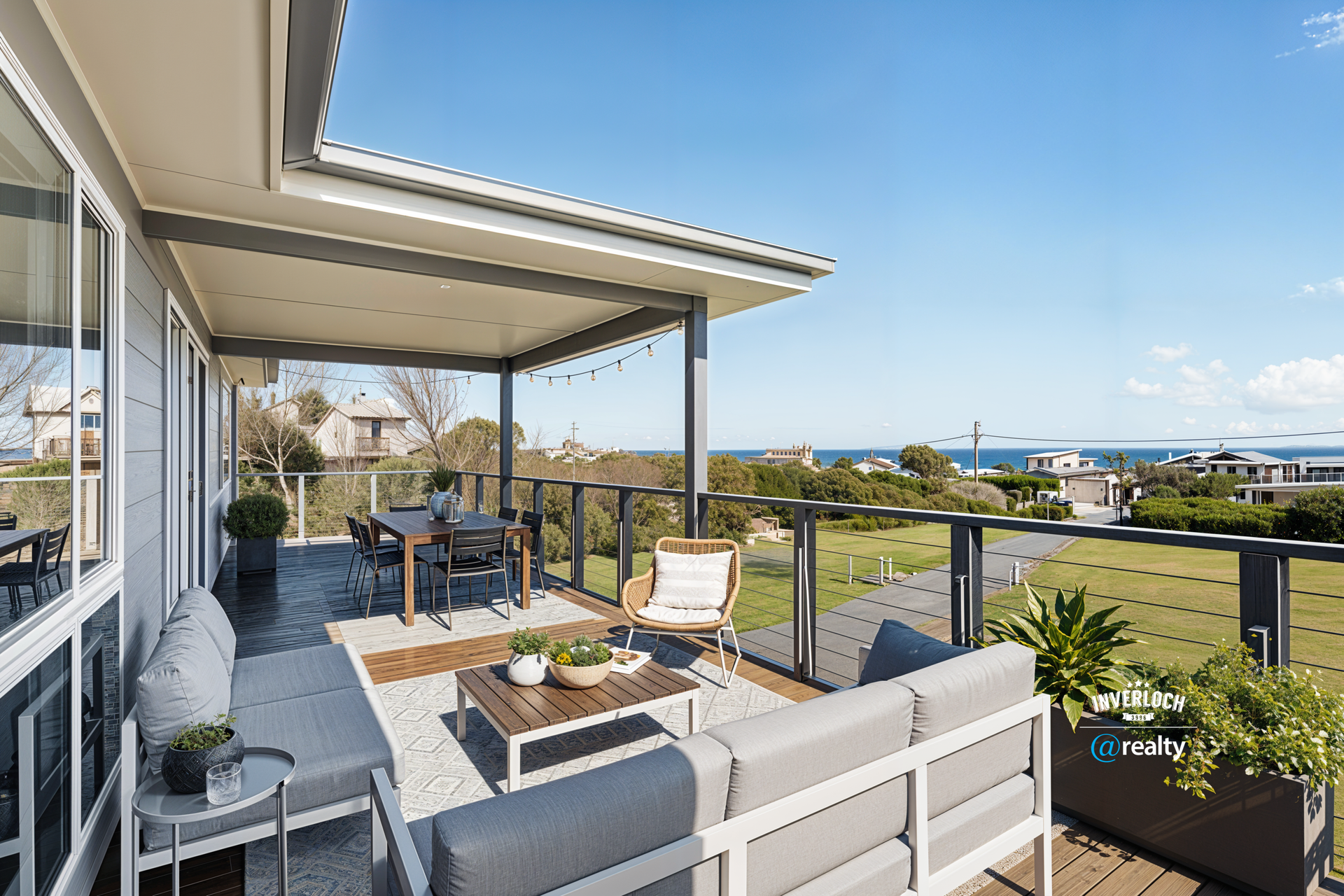 Outdoor patio with seating, dining table, and ocean view on a sunny day.