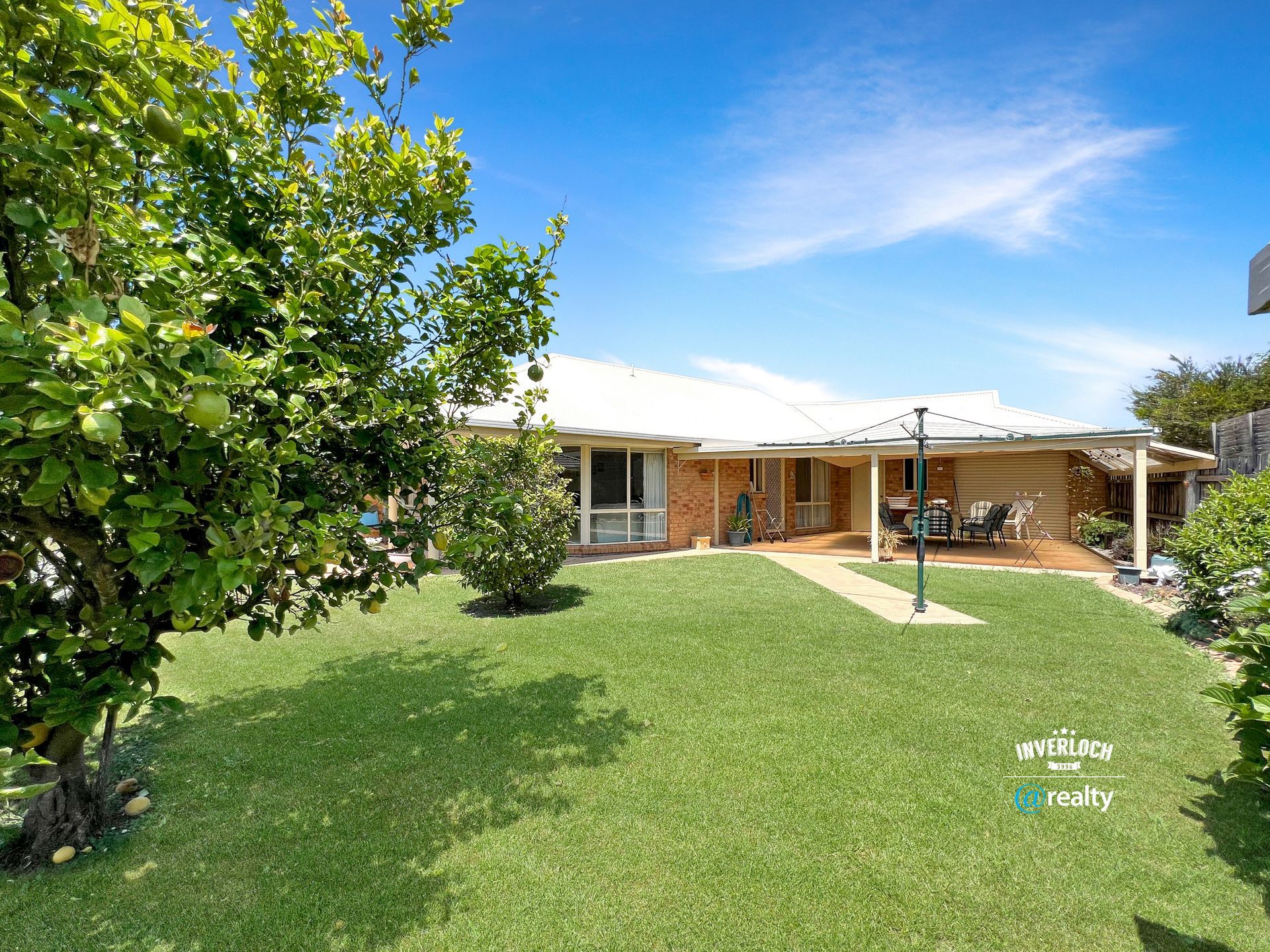 A house with a large lawn and a tree in front of it.
