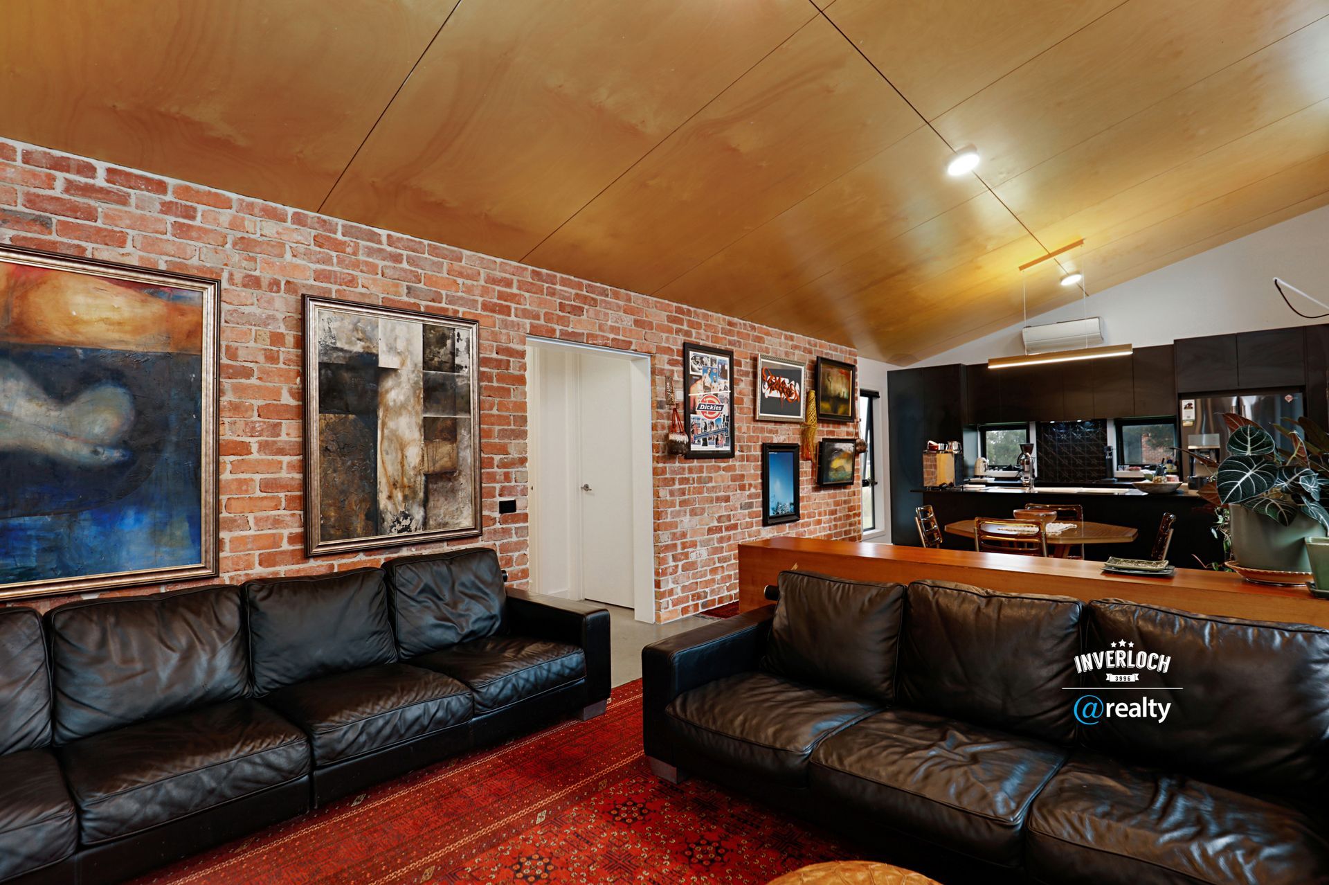 A living room with a black leather couch and a brick wall.