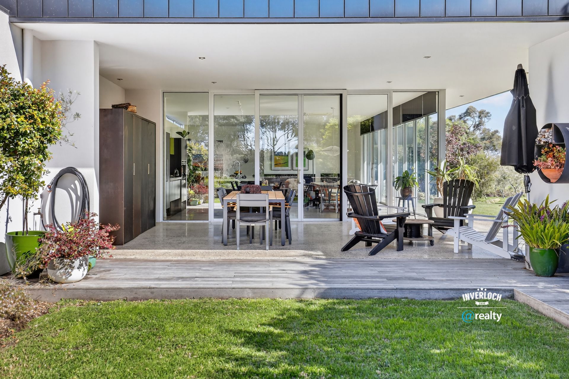 Patio with sliding glass doors, table, chairs, plants, and green grass.