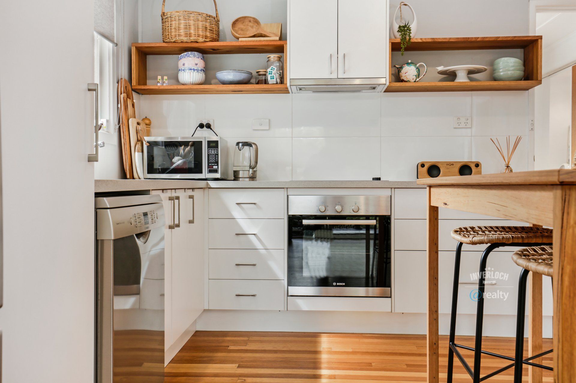 A kitchen with white cabinets , stainless steel appliances , and wooden floors.