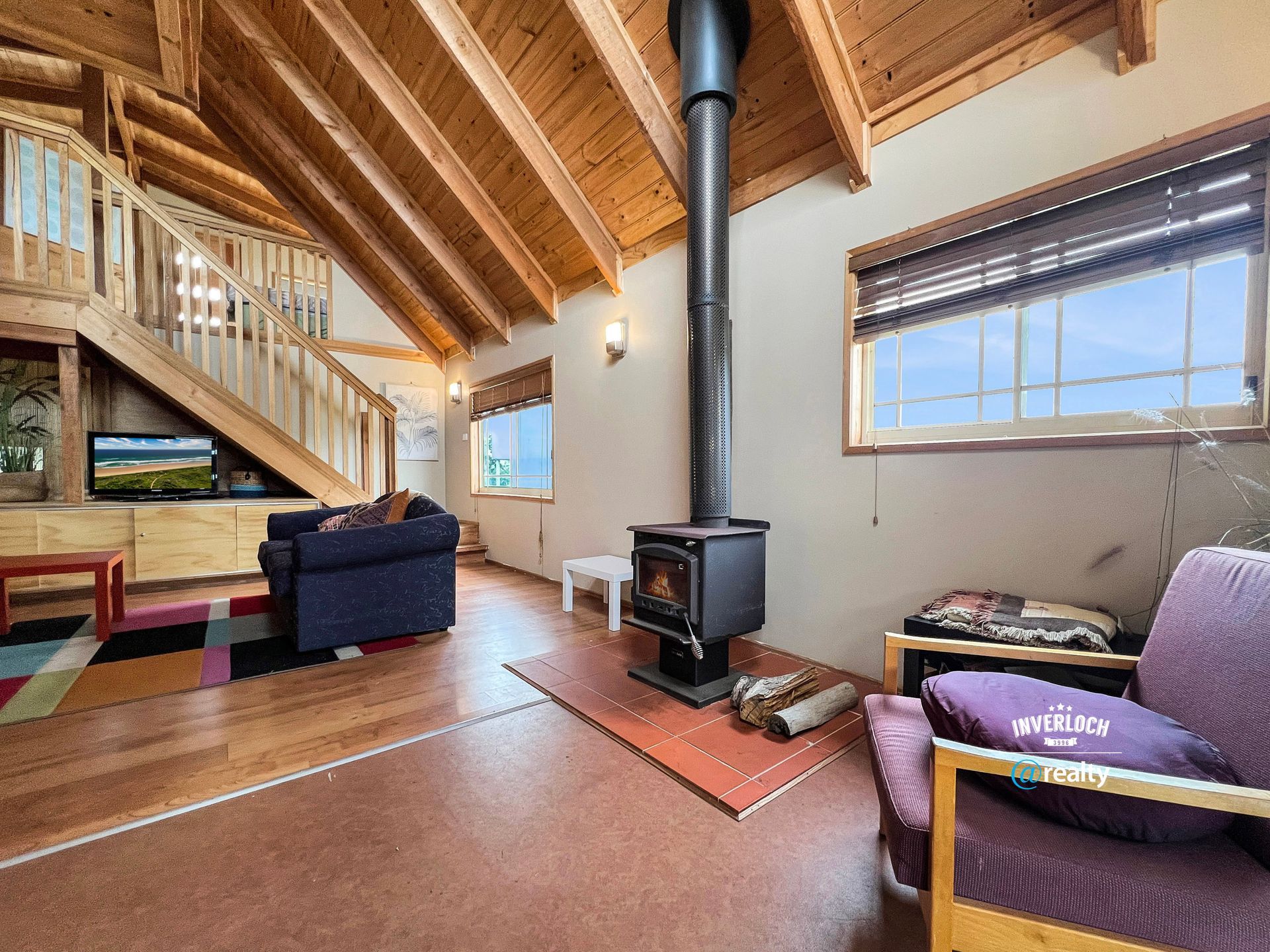 A living room with a wood stove , couch , chair and television.
