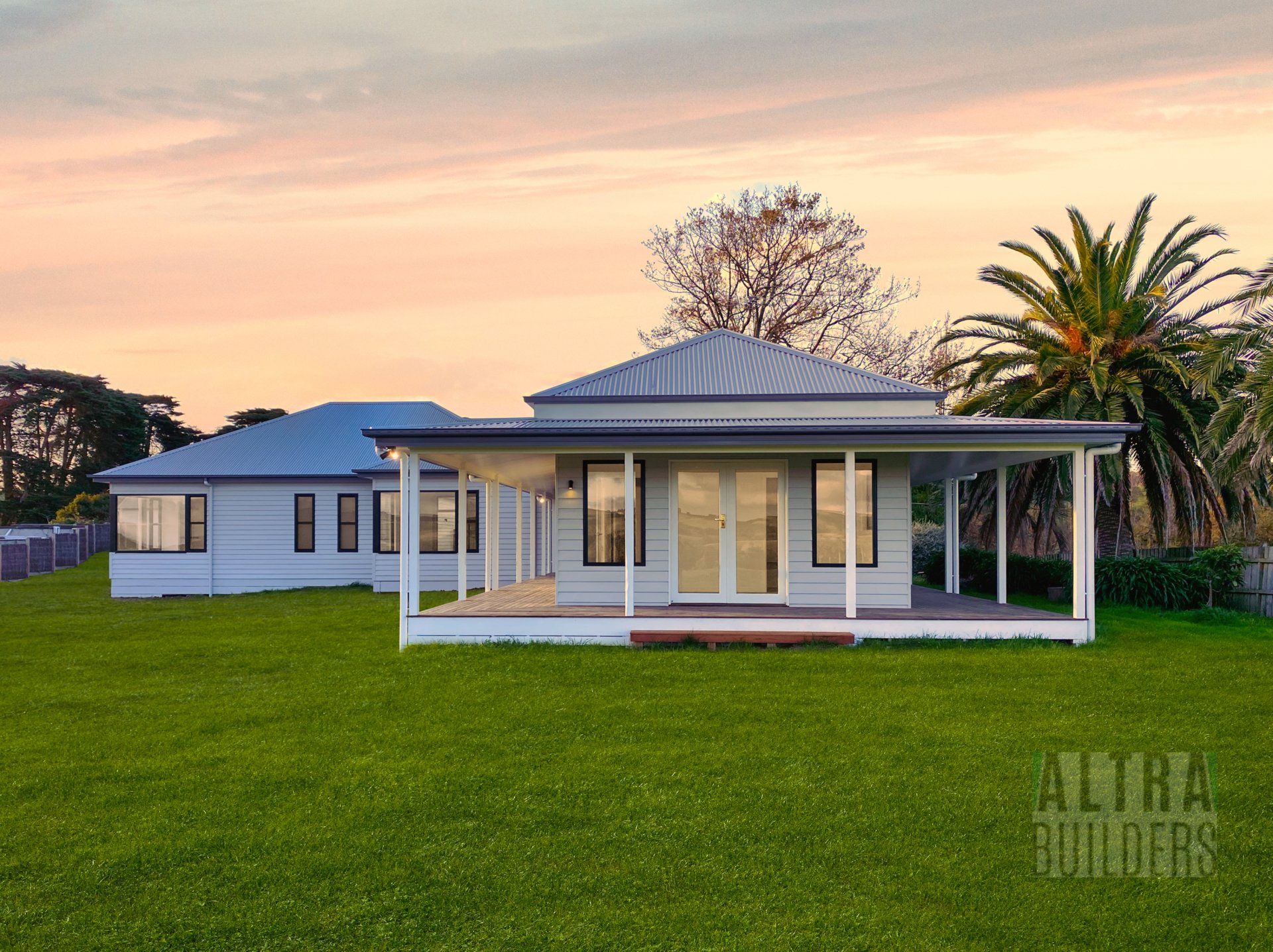 A large white house with a porch and palm trees in front of it