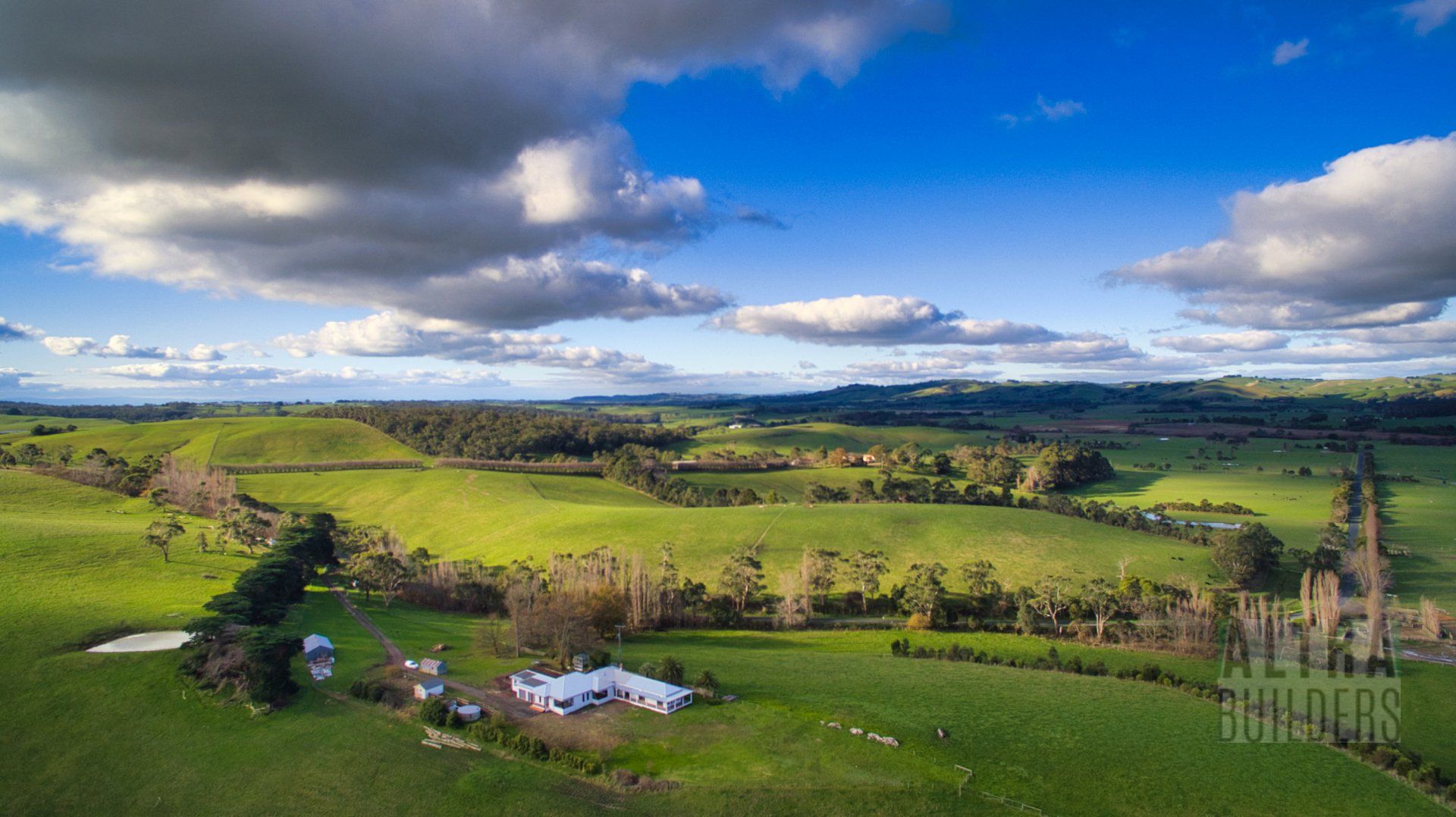 An aerial view of a lush green field with a blue sky and clouds.