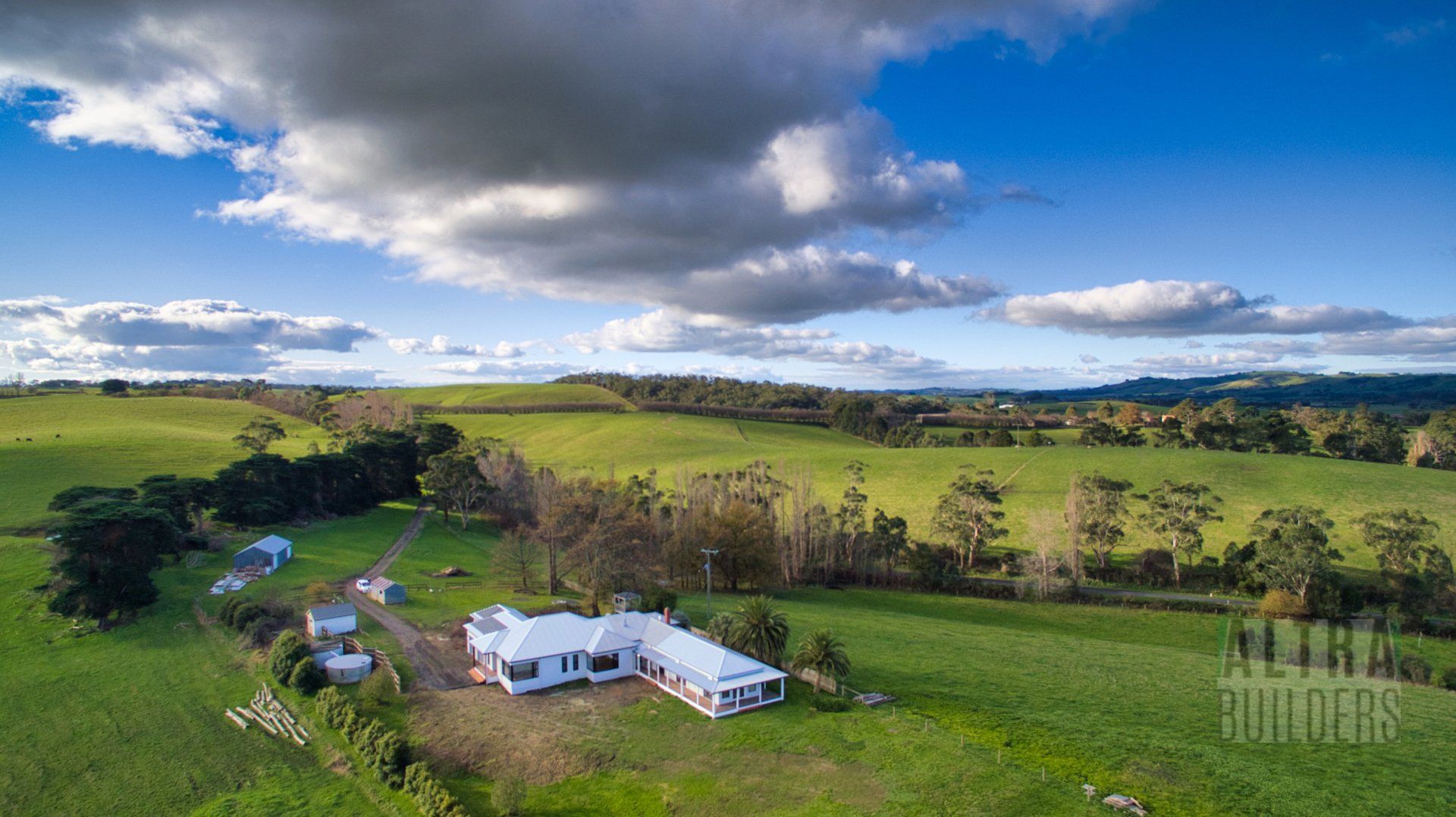 An aerial view of a house in the middle of a grassy field.