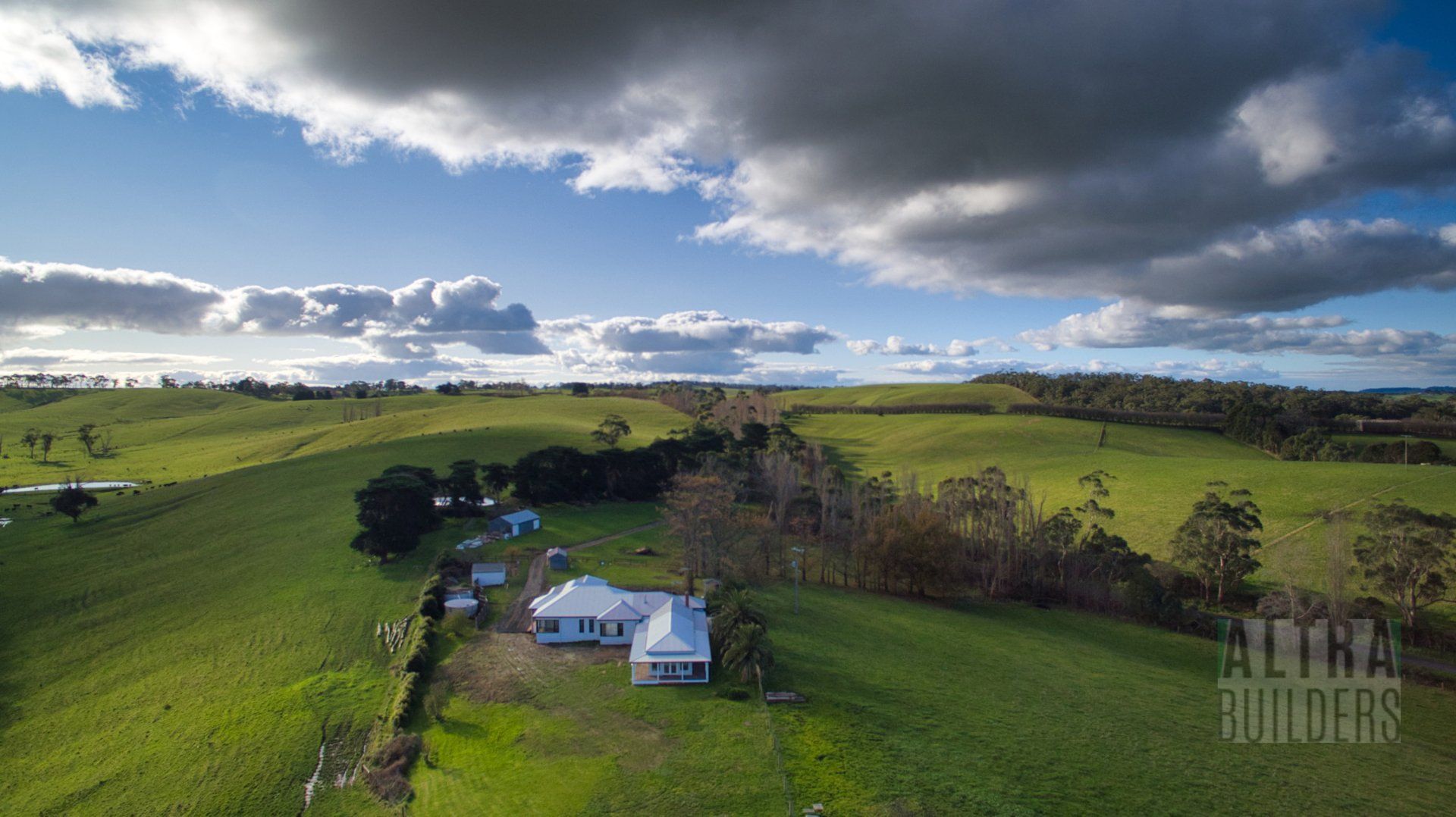 An aerial view of a house in the middle of a grassy field.