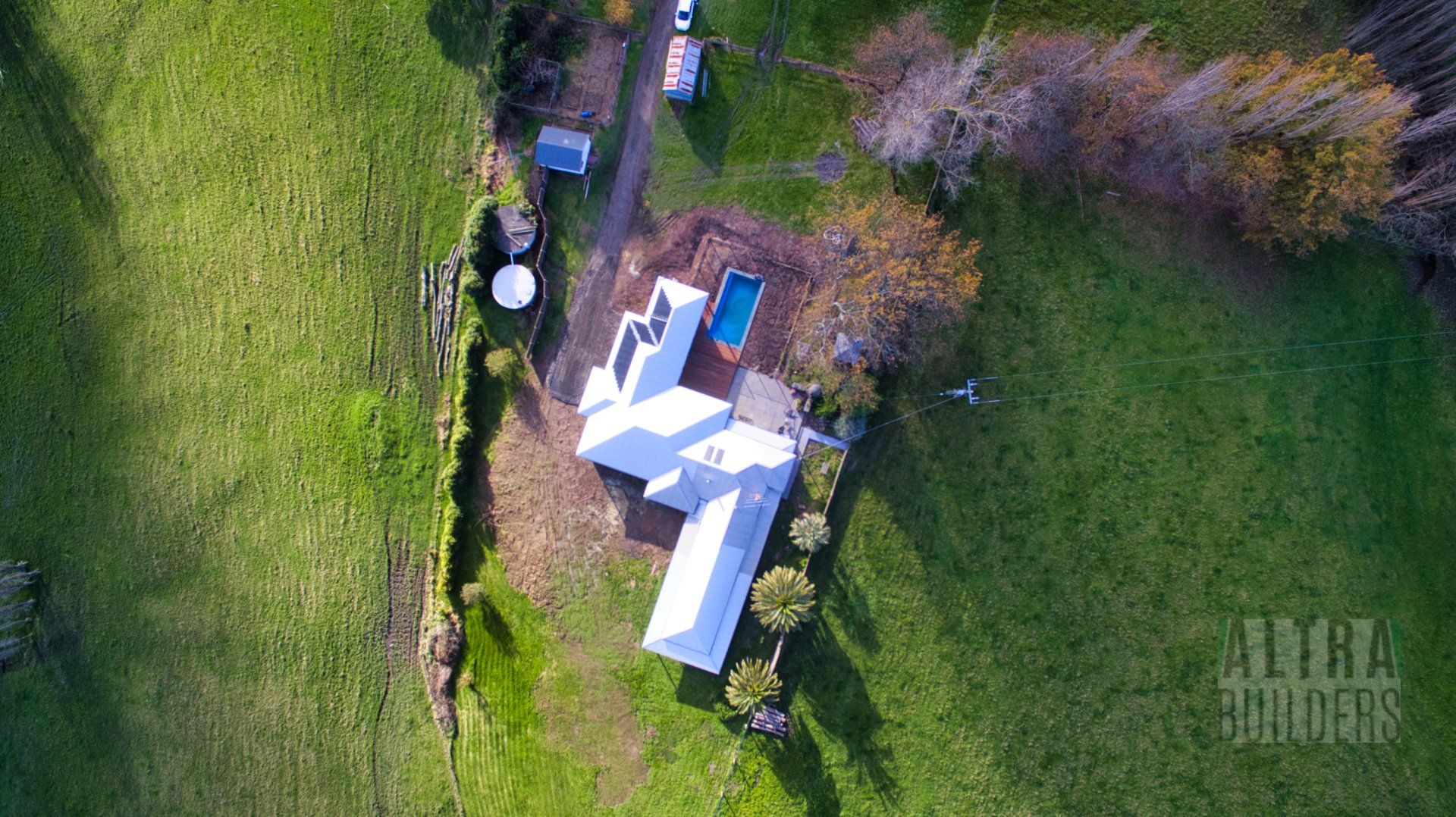 An aerial view of a house in the middle of a grassy field.
