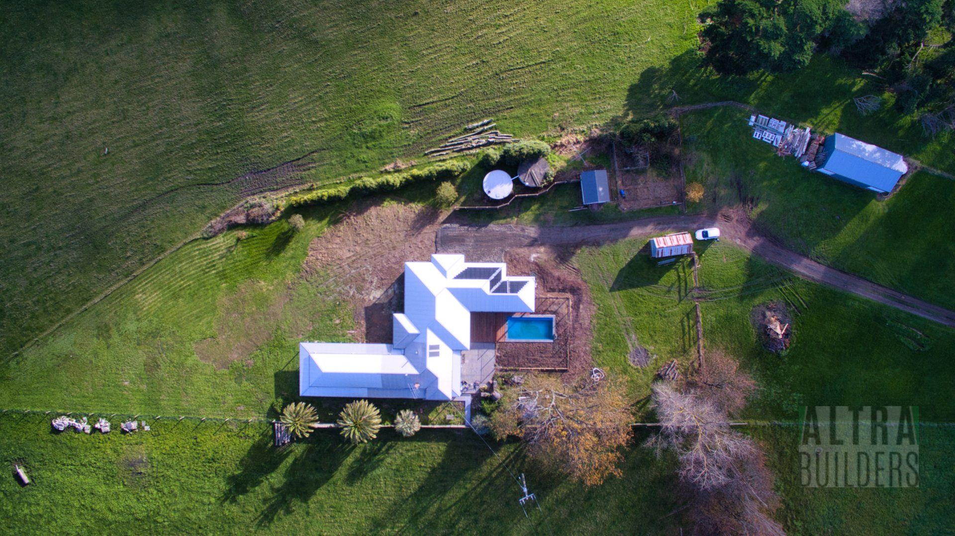 An aerial view of a house in the middle of a grassy field.