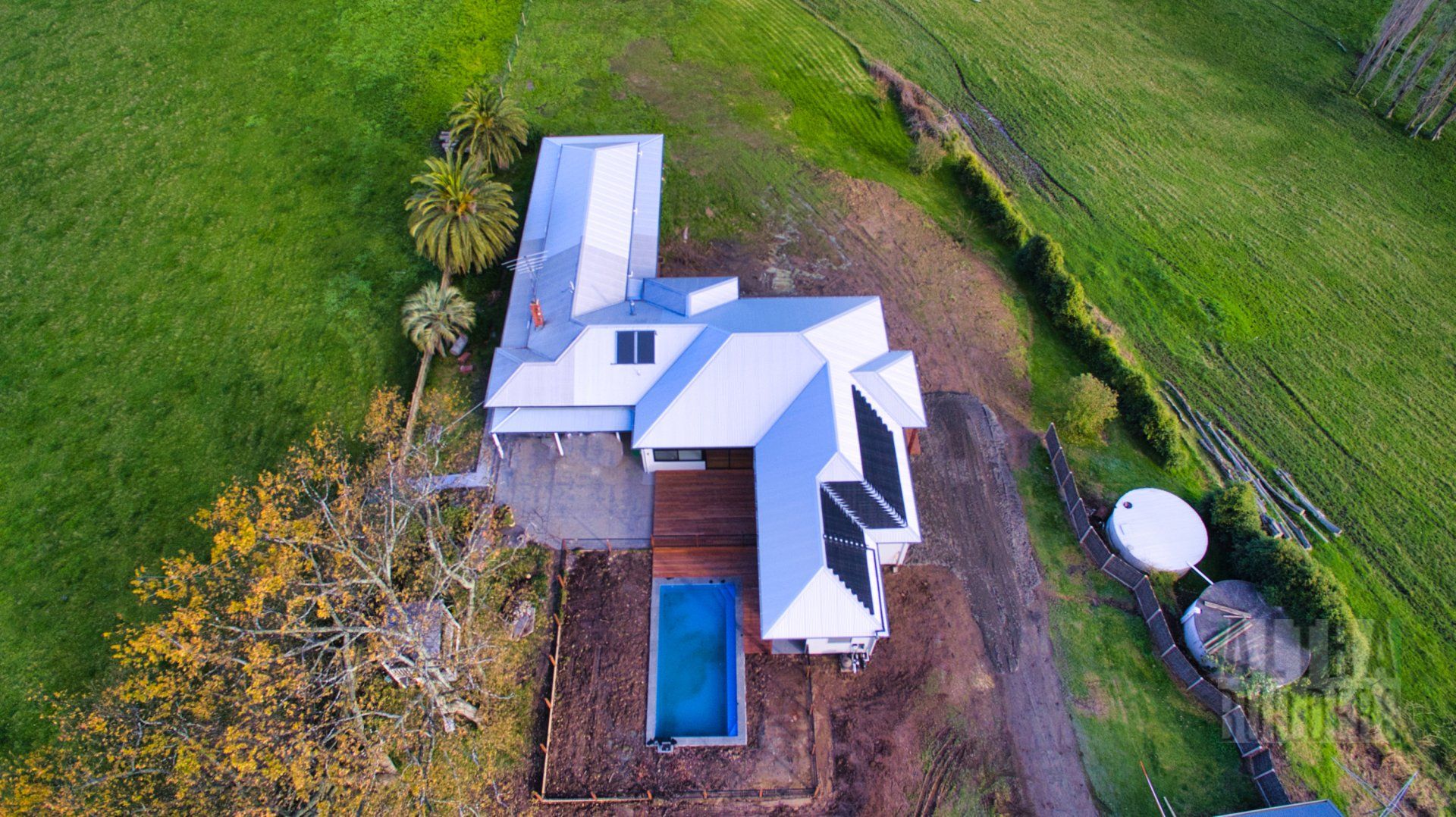 An aerial view of a house with a pool in the middle of a field.