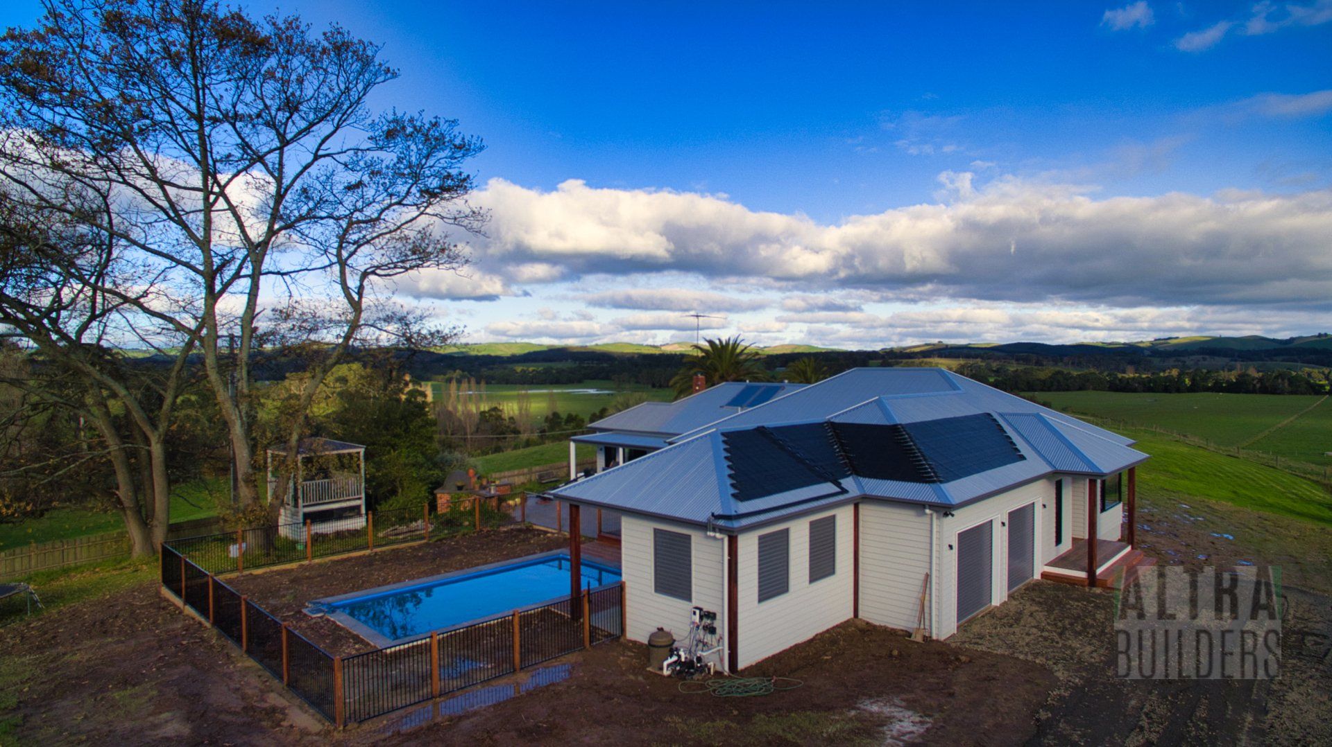 An aerial view of a house with a swimming pool in the backyard.