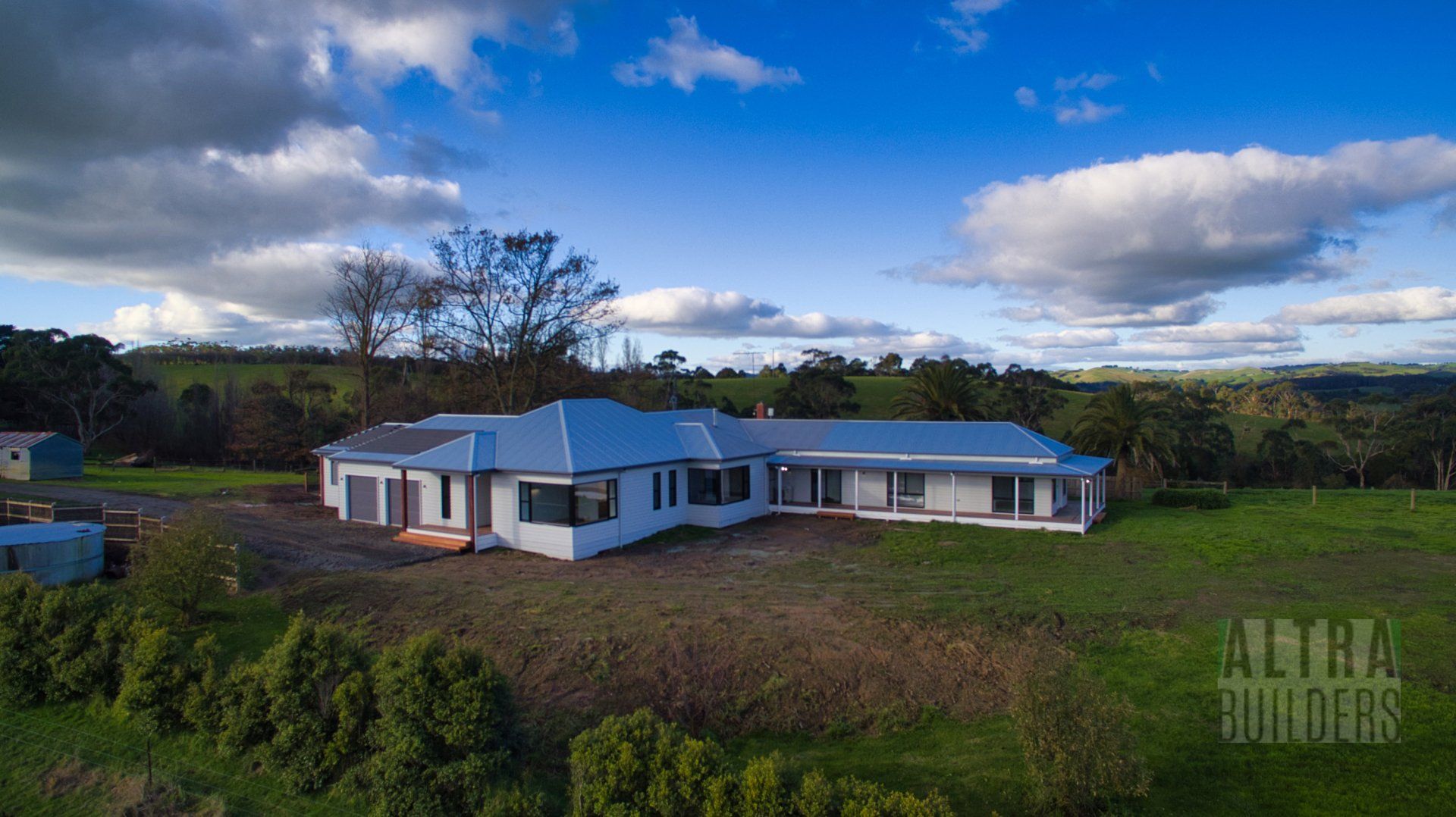 An aerial view of a large white house in the middle of a grassy field.