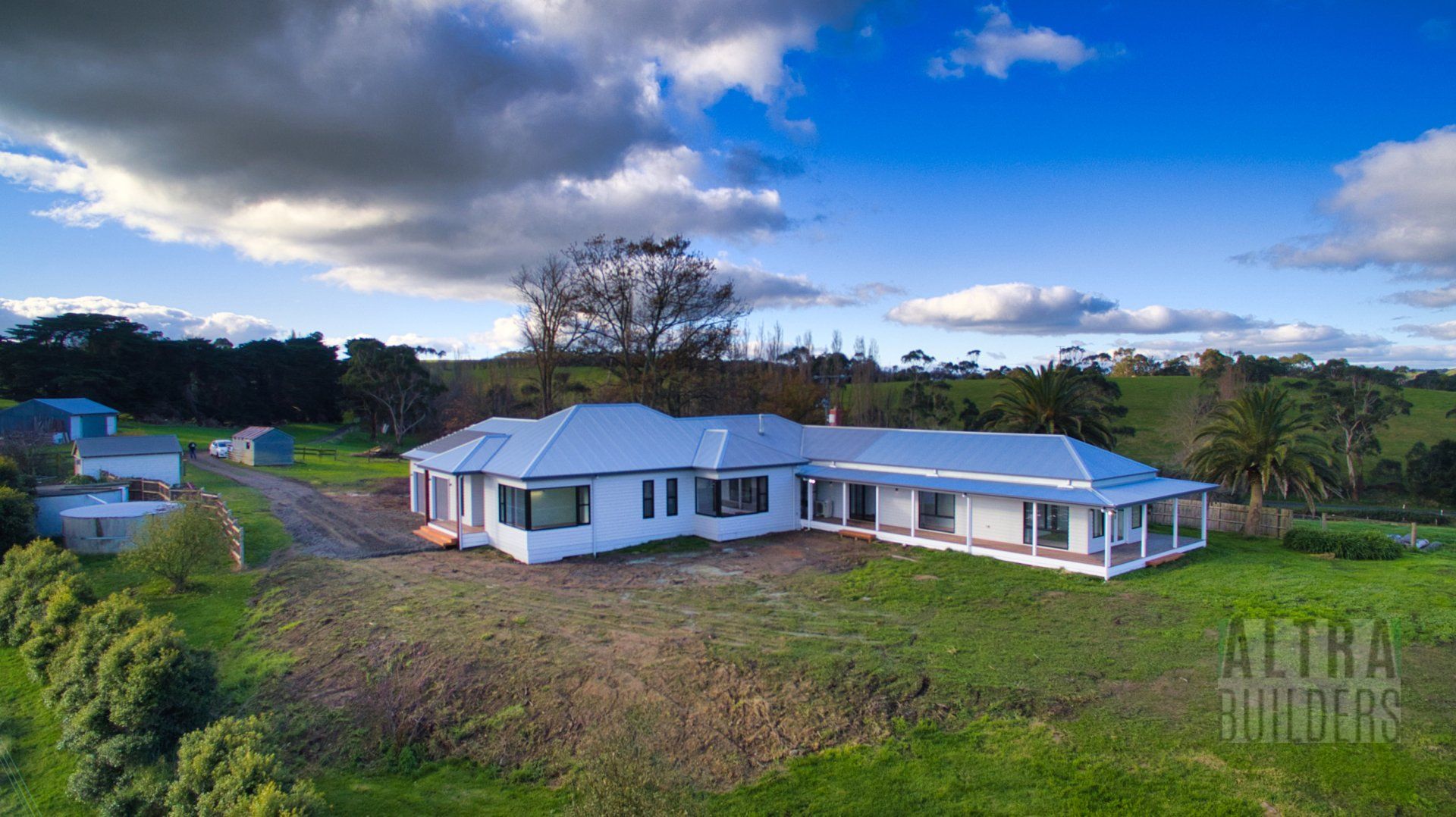 An aerial view of a large white house in the middle of a grassy field.
