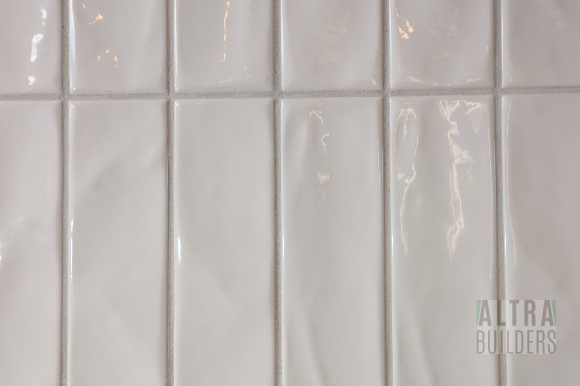 A close up of a white tile wall.