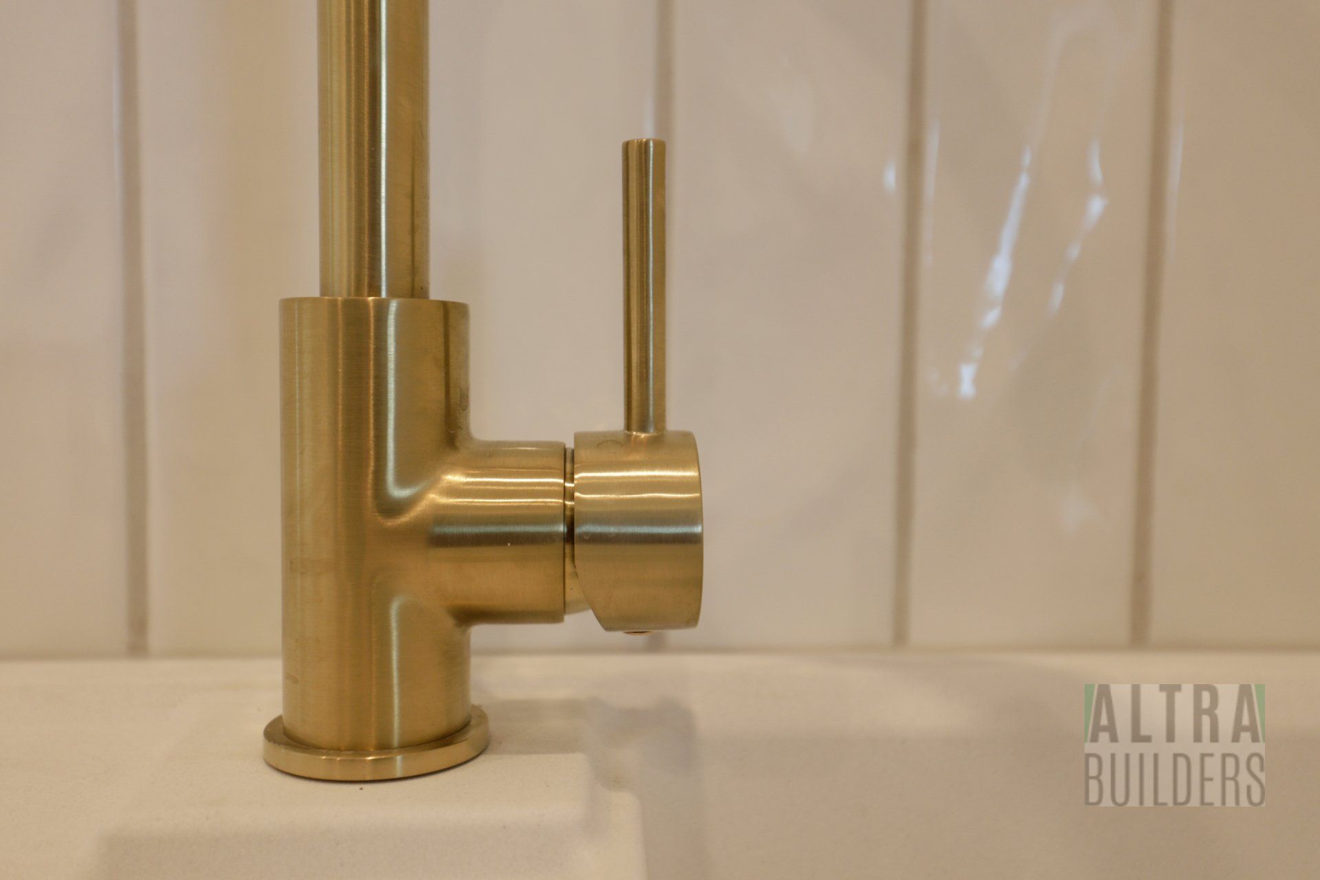 A close up of a gold kitchen faucet on a sink.