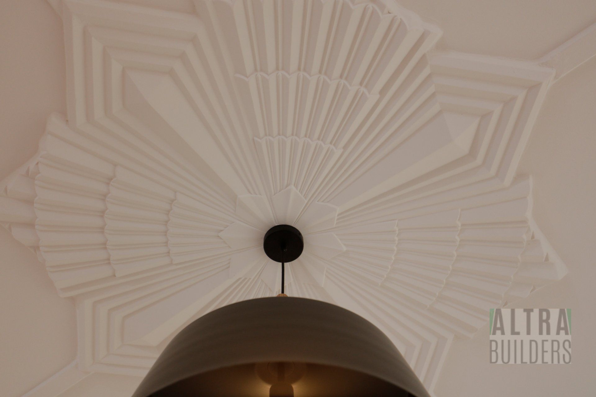 A light hanging from a ceiling with altra builders written on the bottom