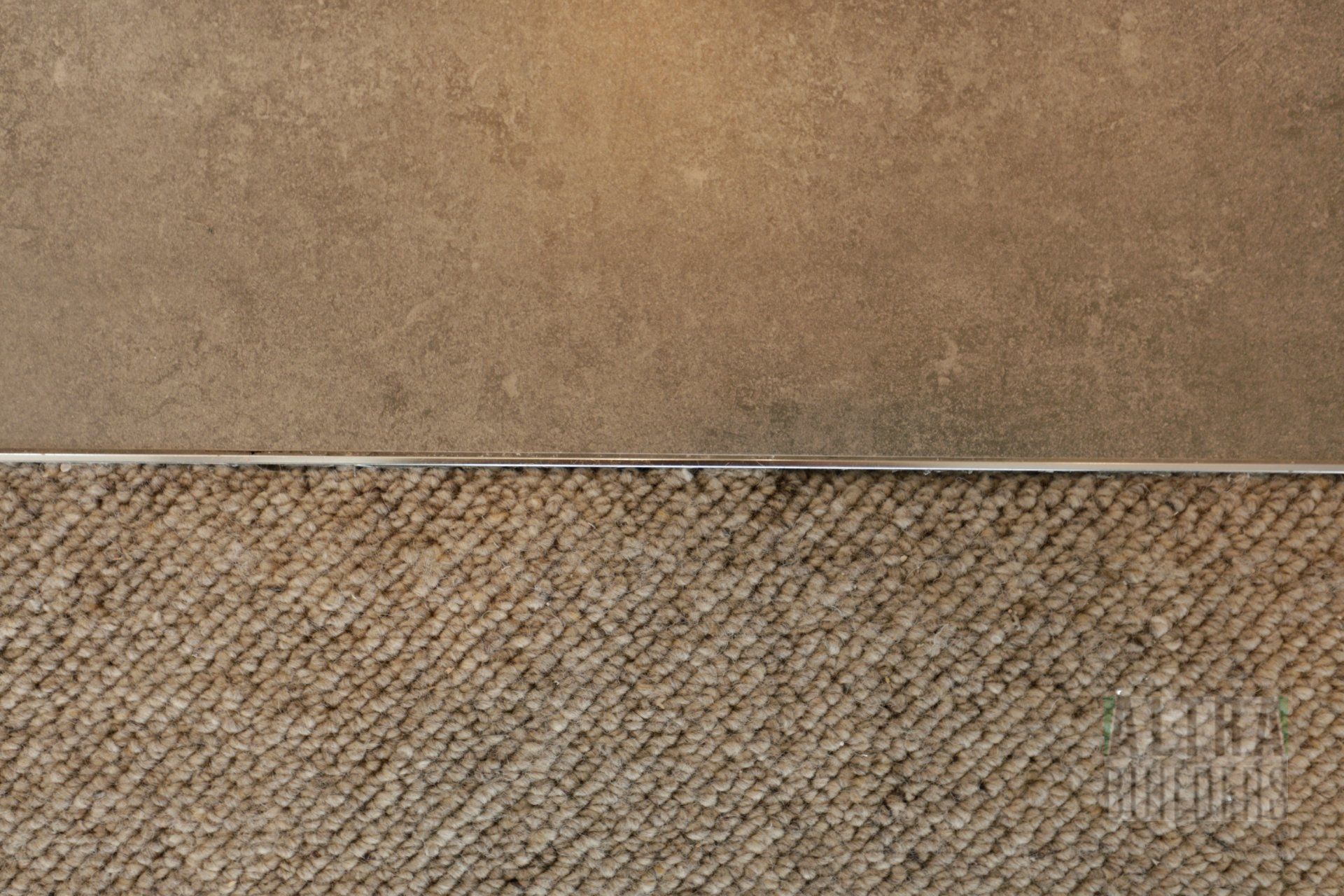 A tile and a carpet are next to each other