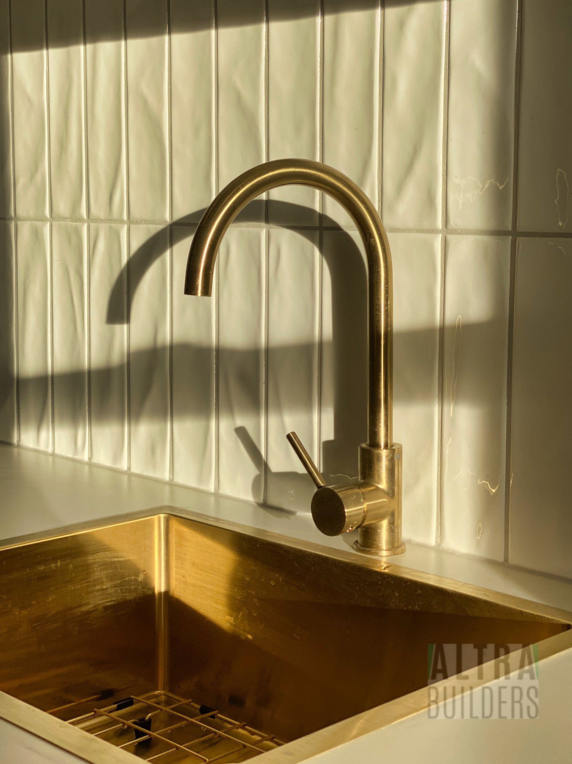 A close up of a gold sink with a faucet in a kitchen.