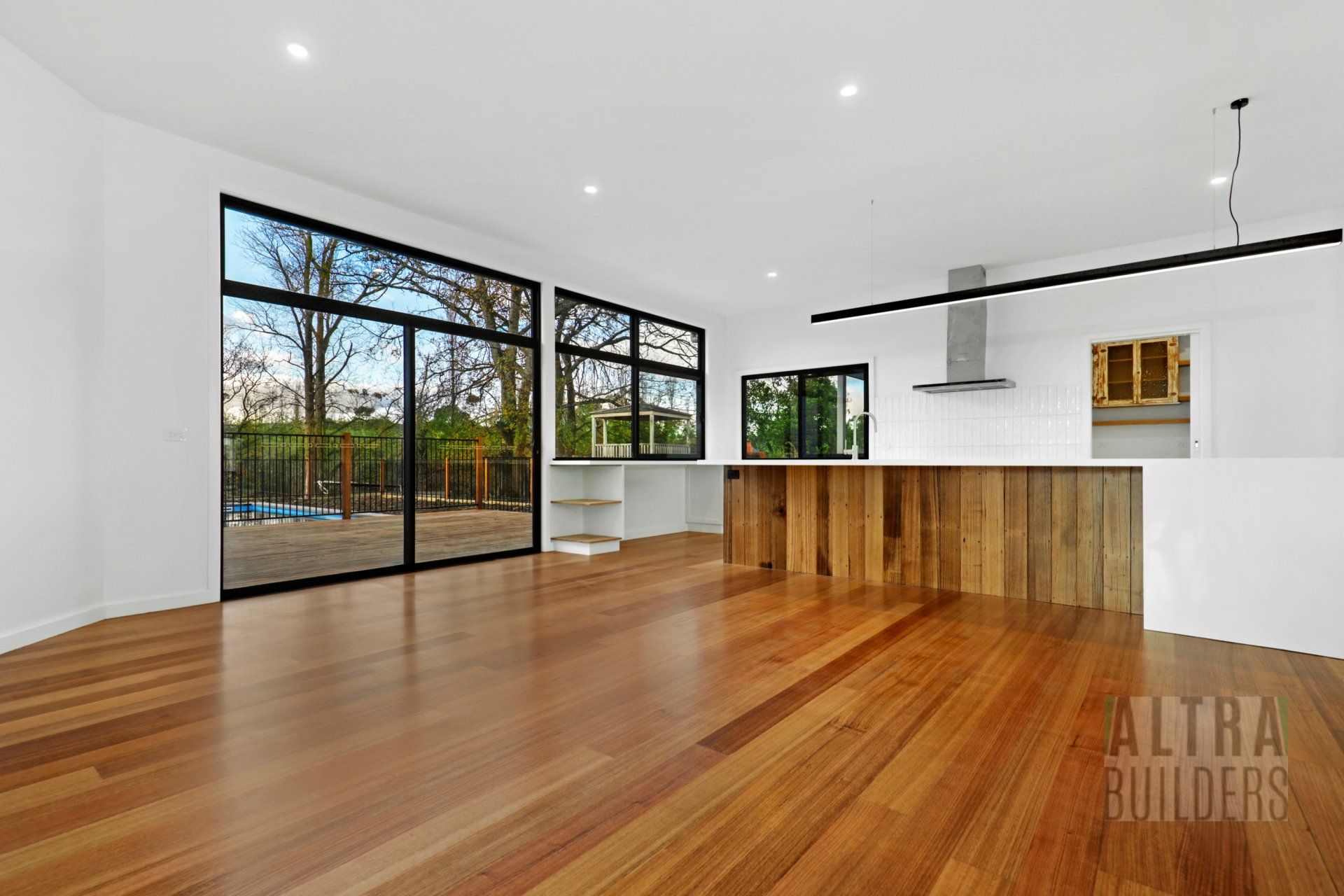 A large empty room with hardwood floors and sliding glass doors.