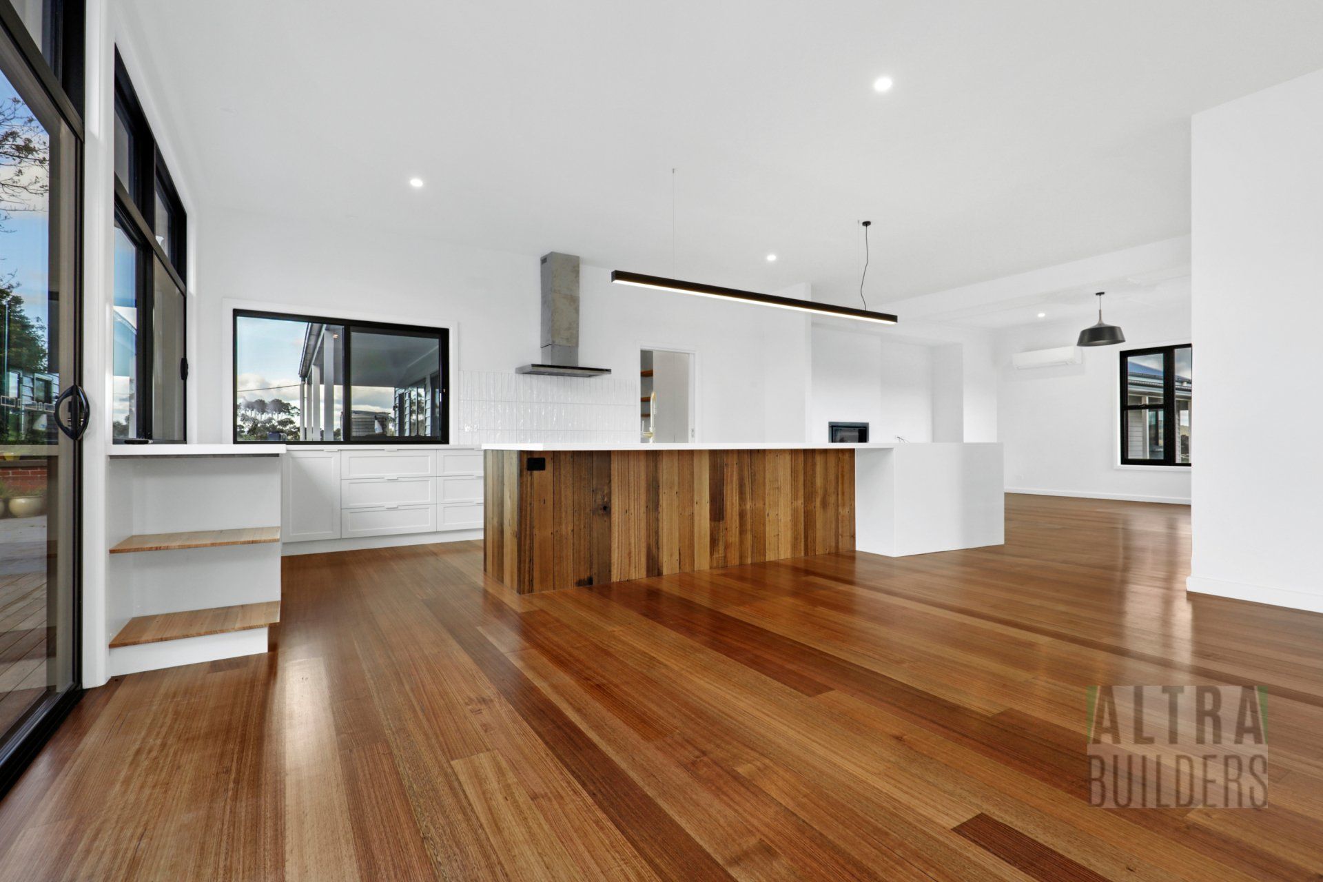 A kitchen with wooden floors and white cabinets in a house.