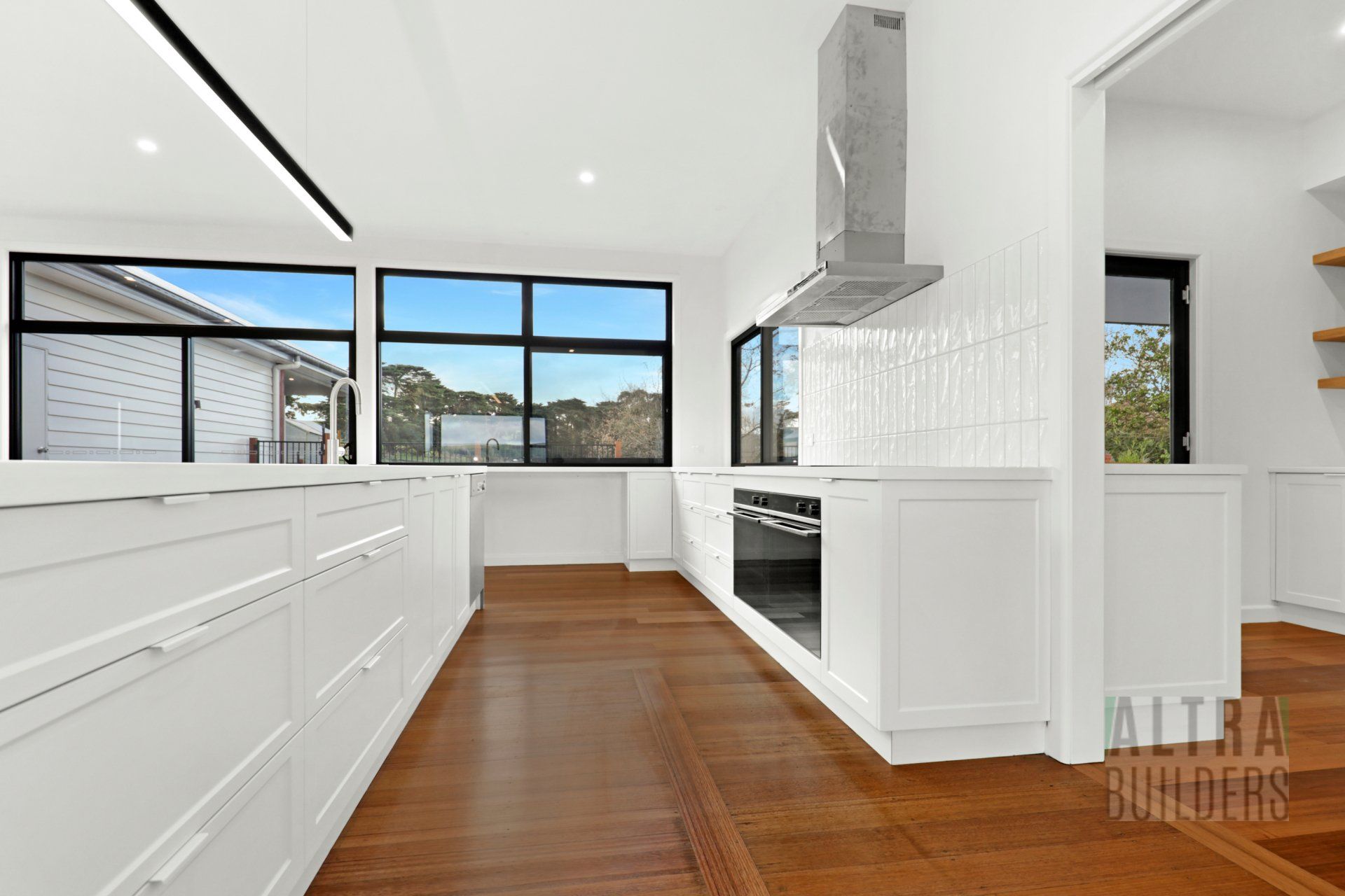 A kitchen with white cabinets and a wooden floor