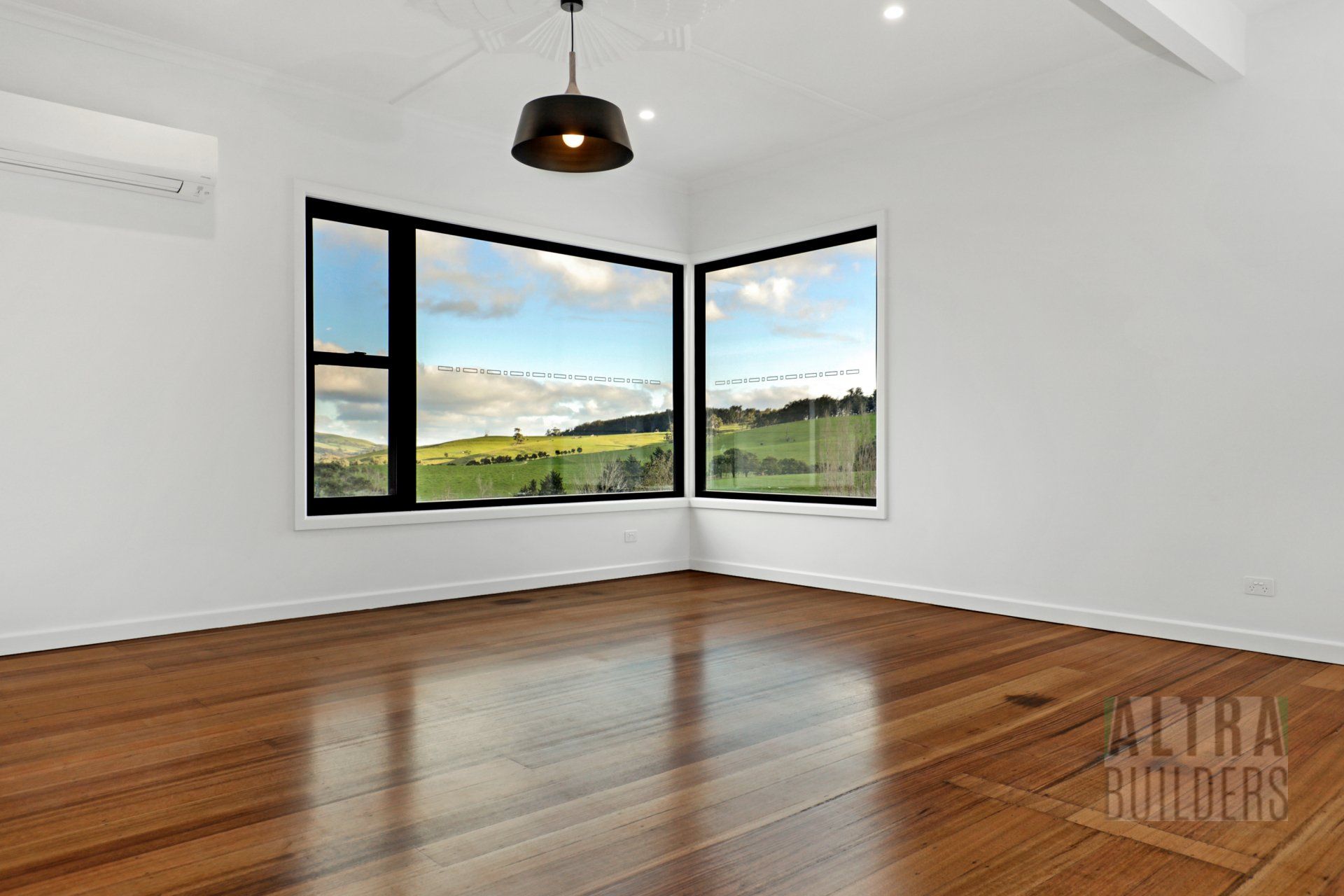 An empty room with hardwood floors and two windows