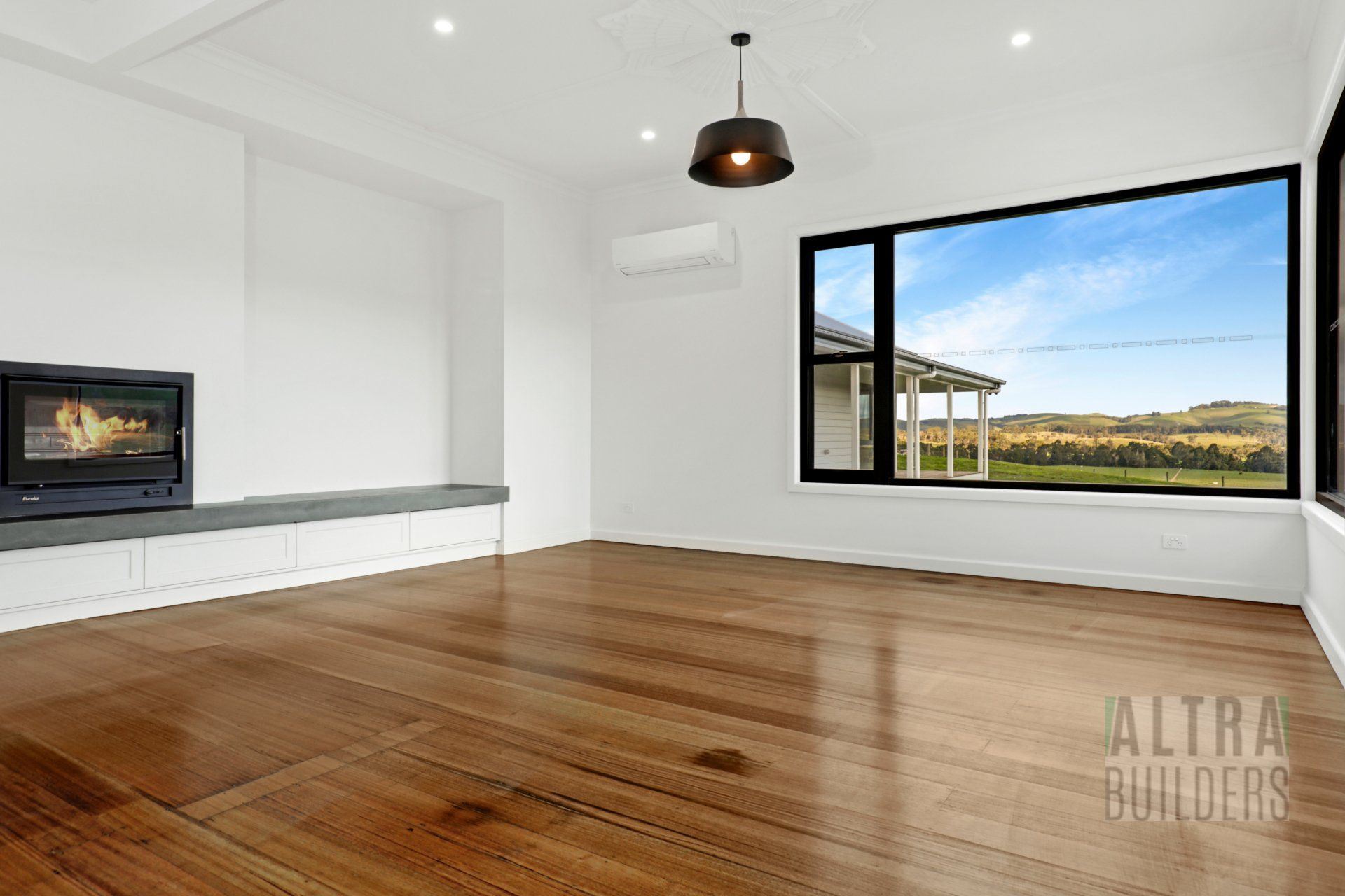 An empty living room with hardwood floors and a fireplace.