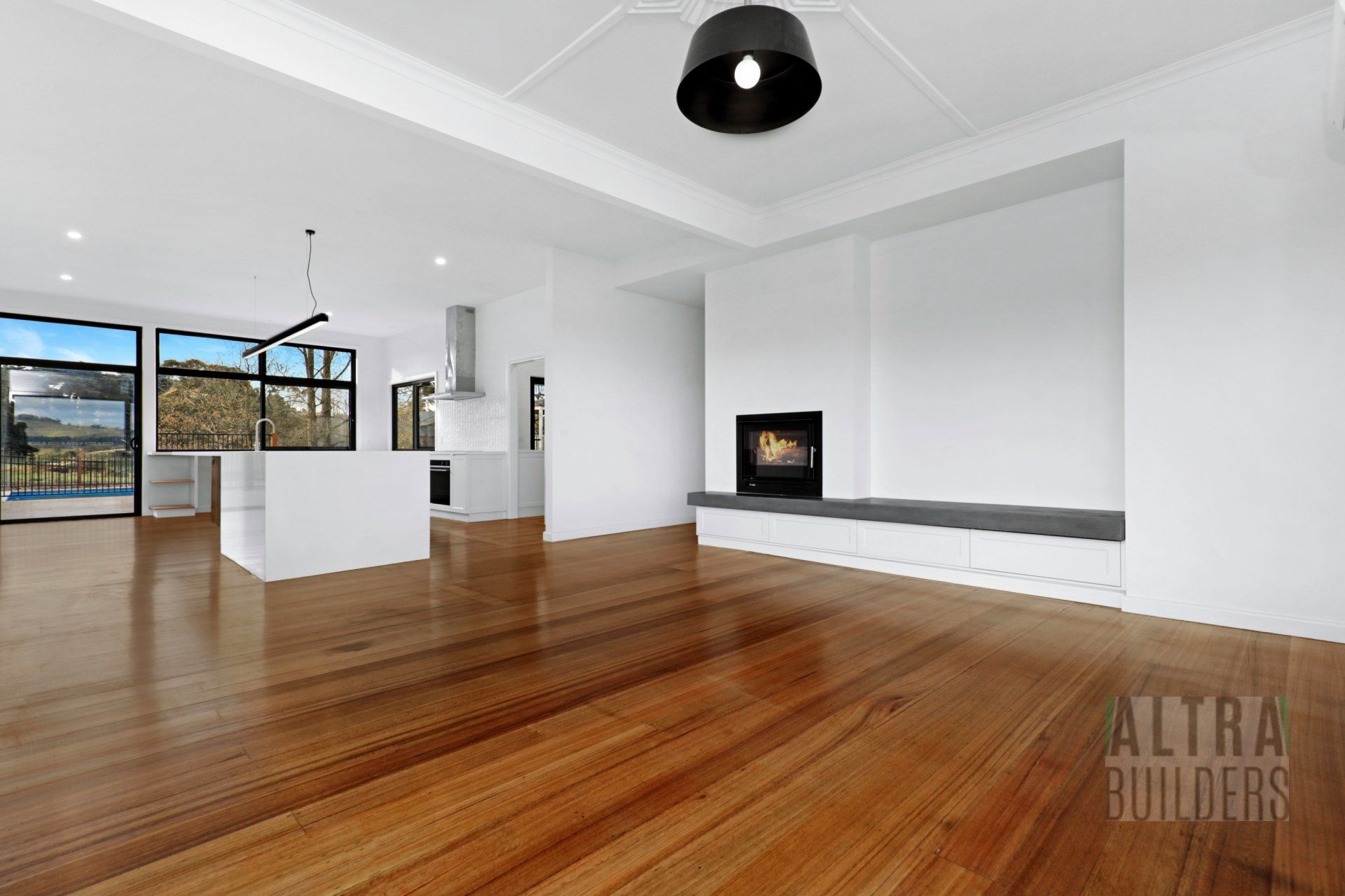 An empty living room with hardwood floors and white walls