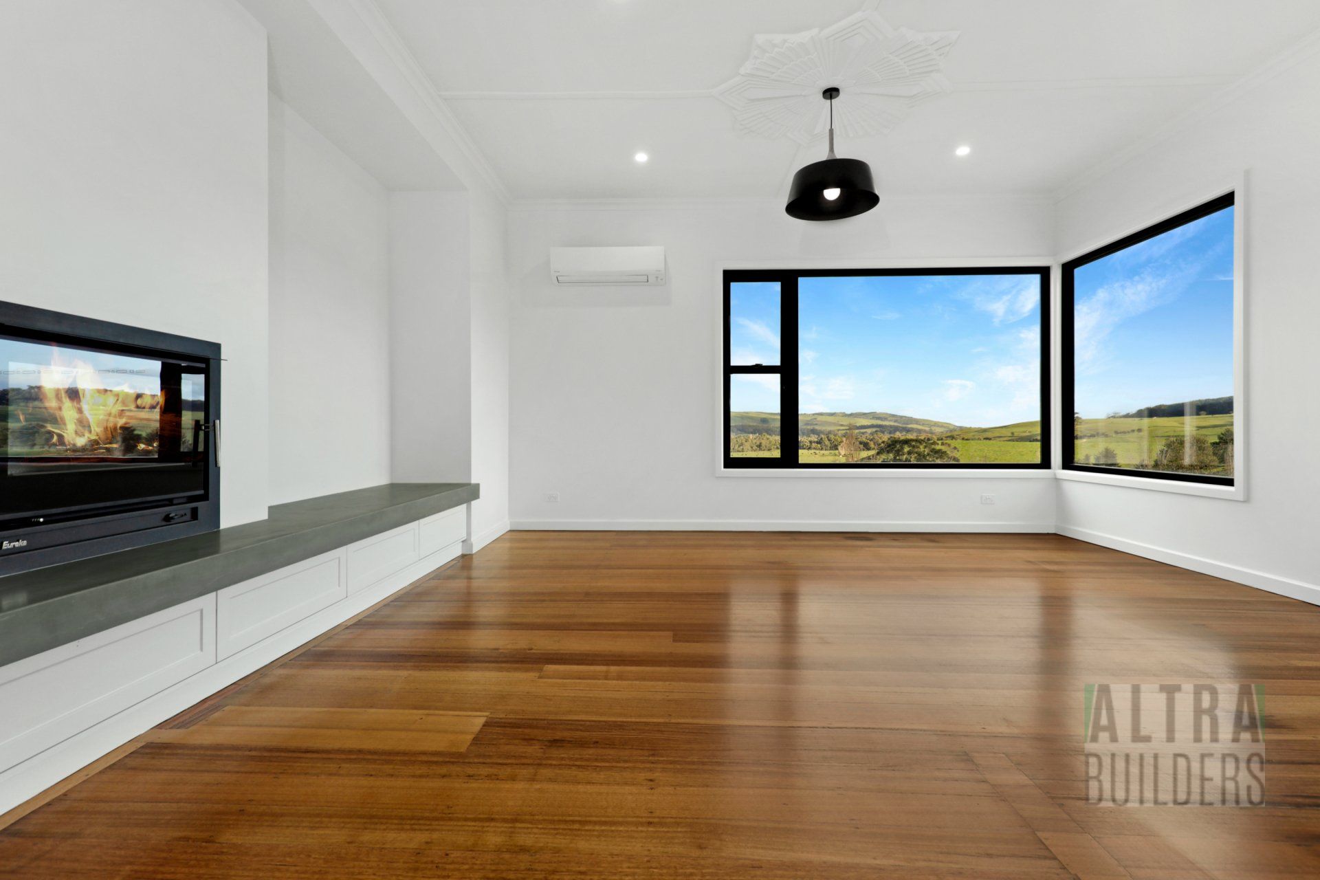 An empty living room with hardwood floors and a fireplace.