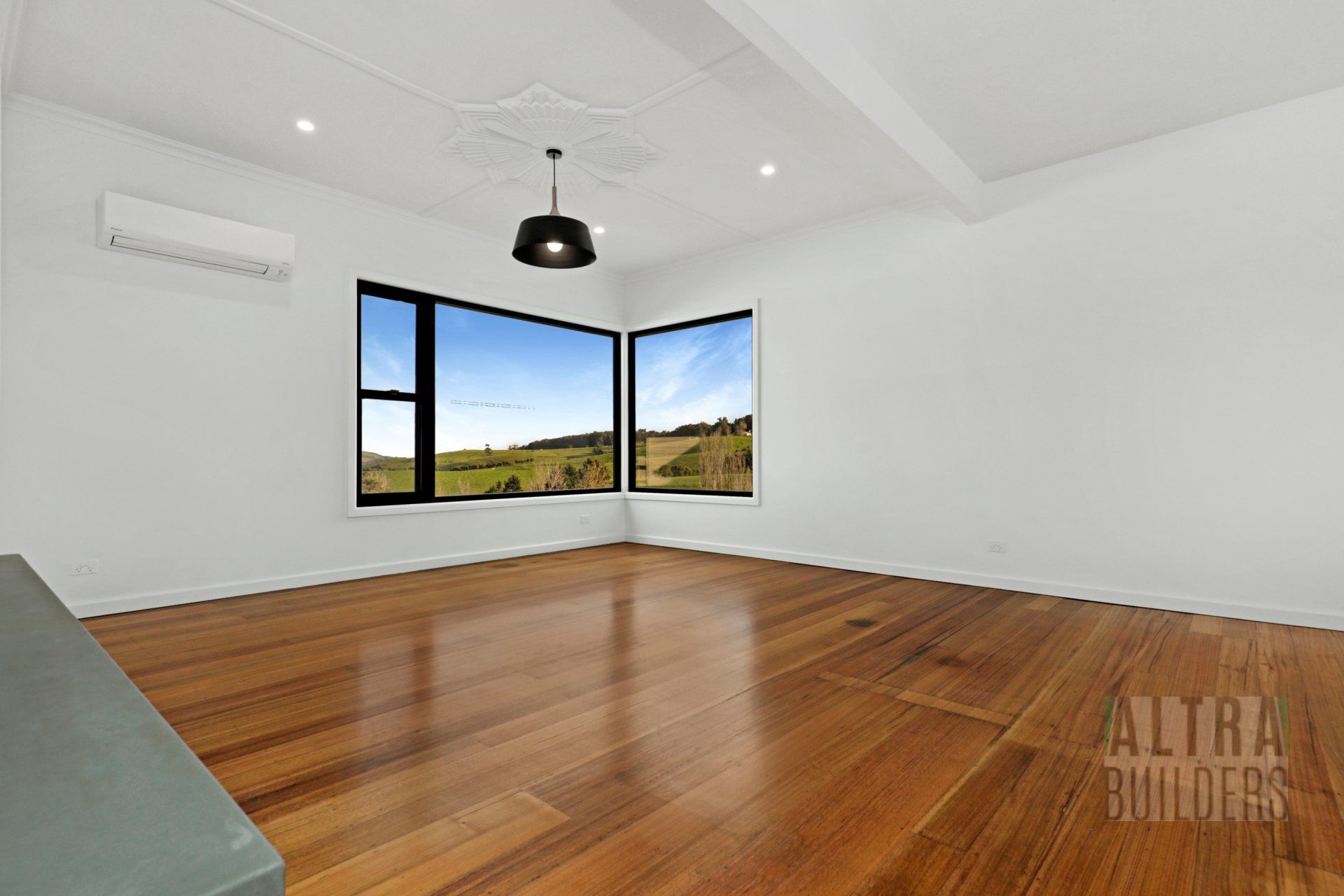 An empty living room with hardwood floors and two windows.