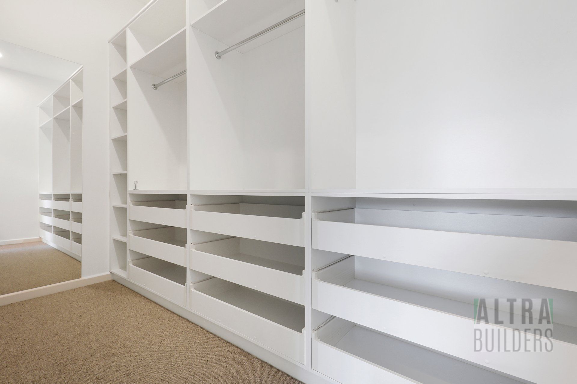 A walk in closet with lots of shelves and drawers.