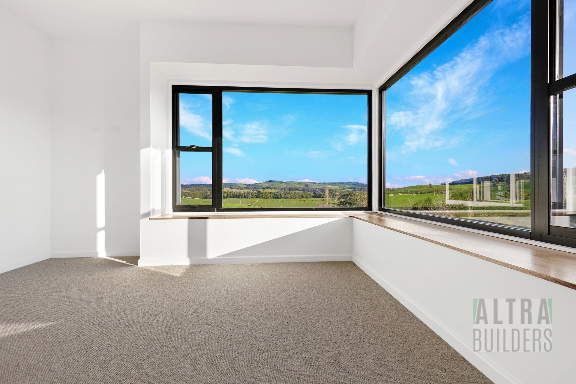 An empty room with a large window with a view of a field.