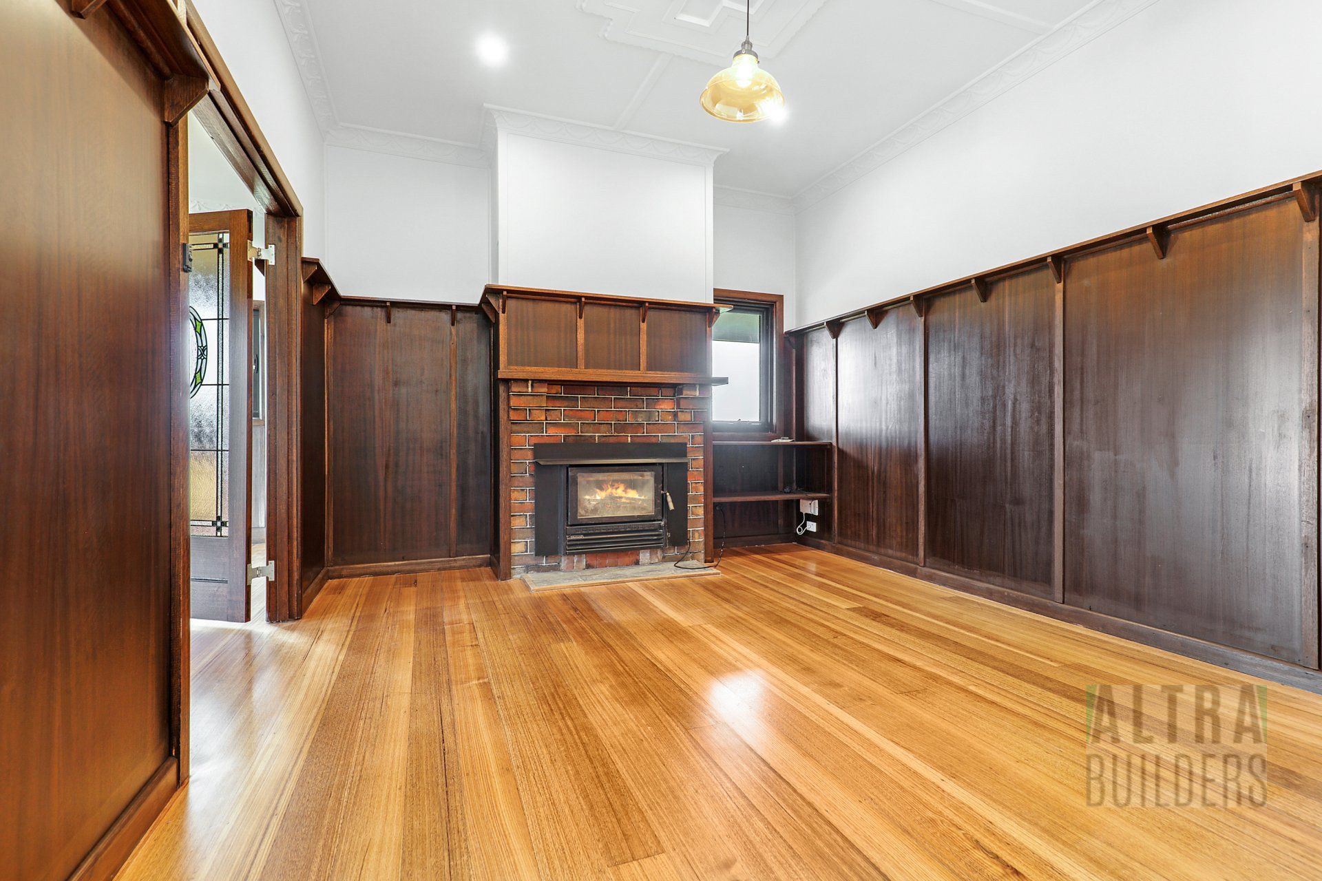 An empty living room with hardwood floors and a fireplace.
