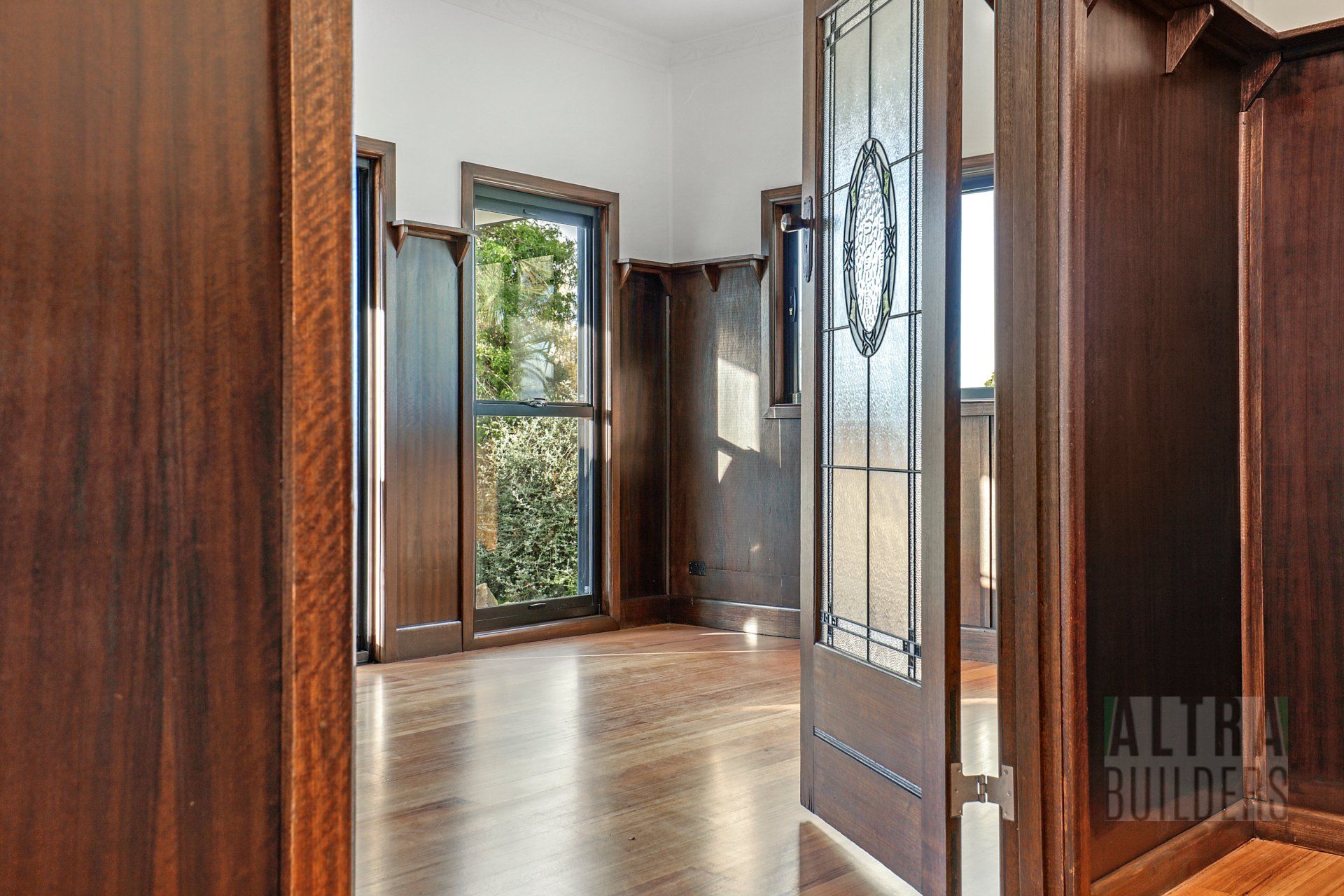 An empty room with hardwood floors and a stained glass door
