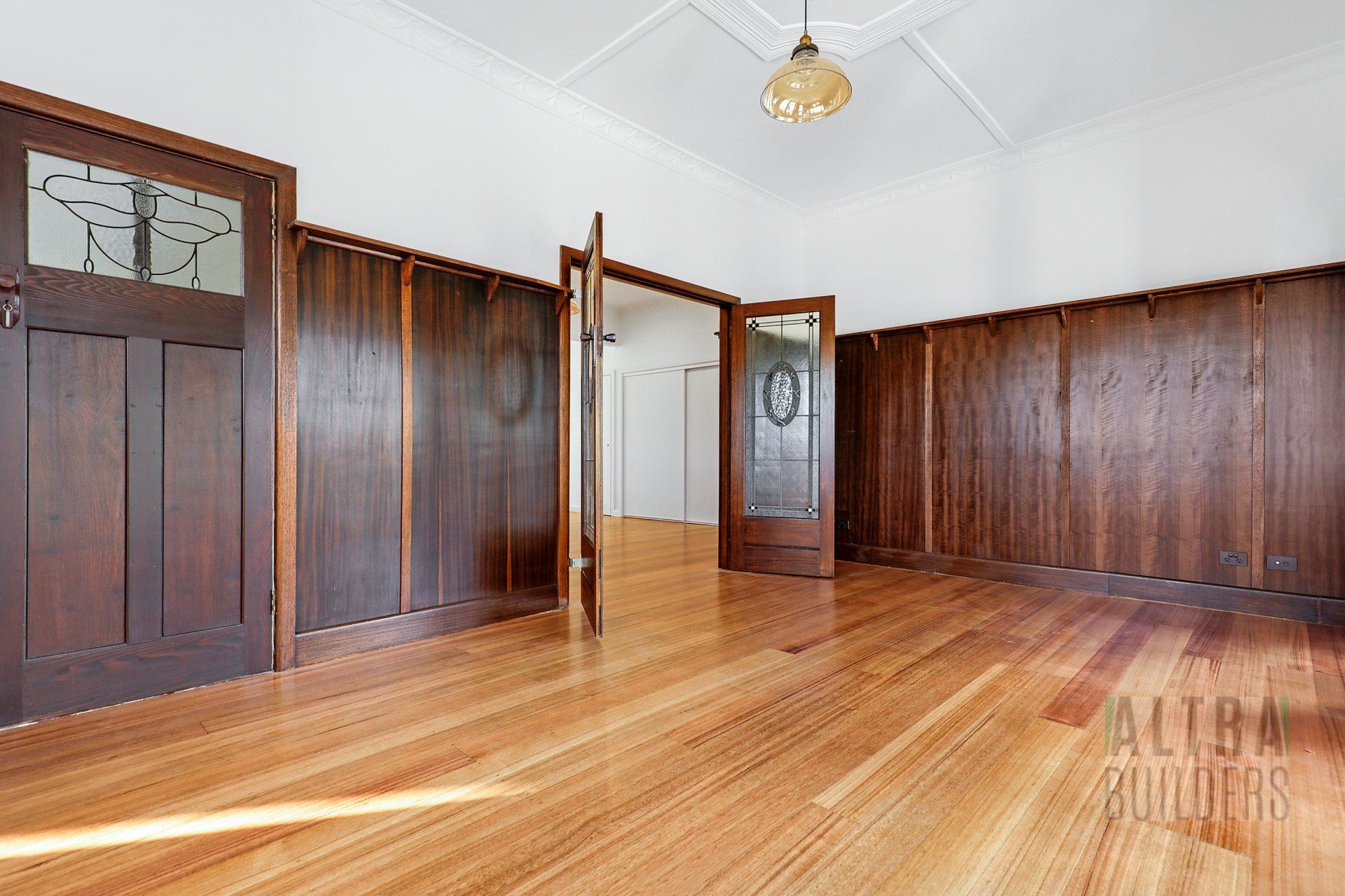 An empty room with wood paneling and hardwood floors