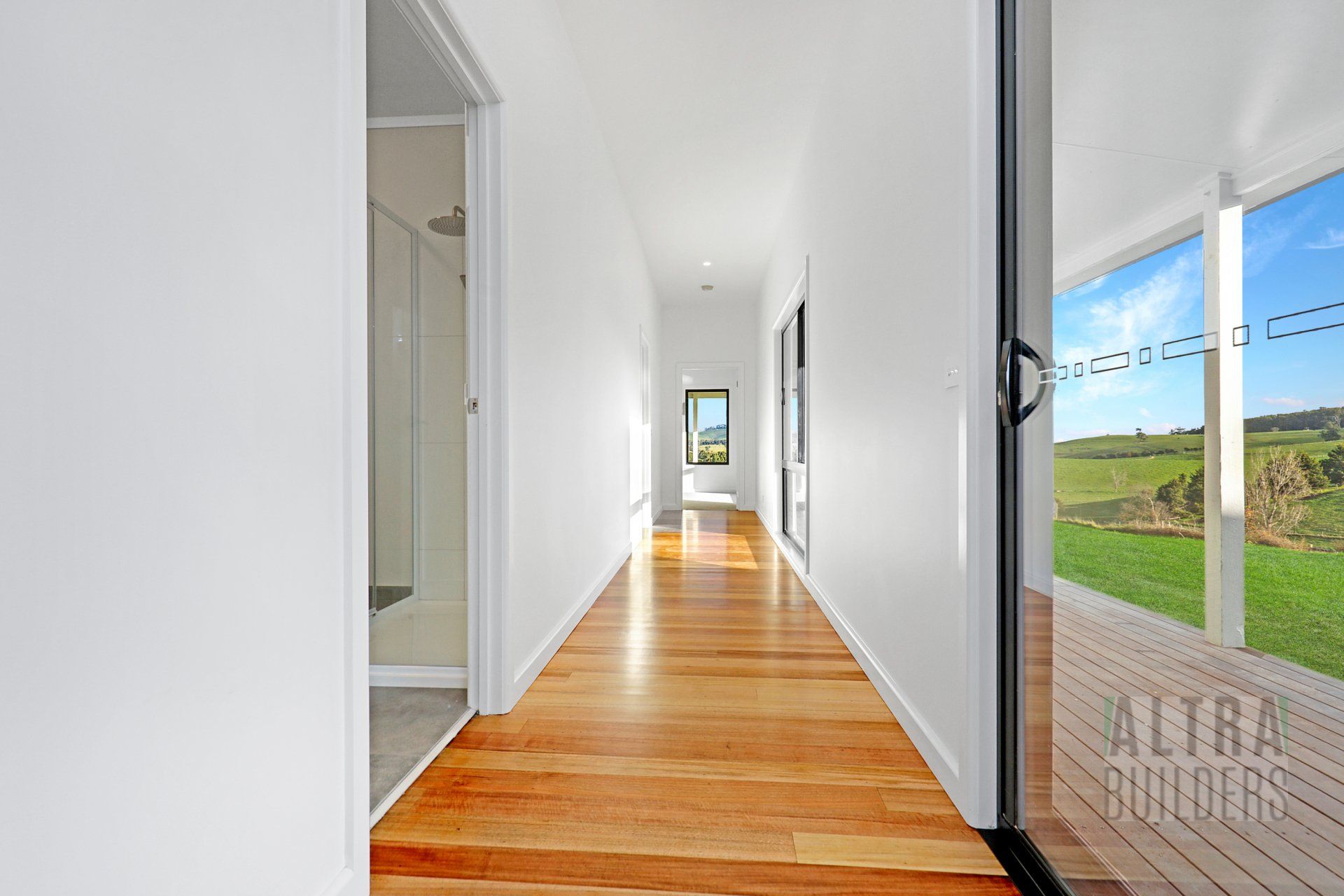 A long hallway with wooden floors and white walls