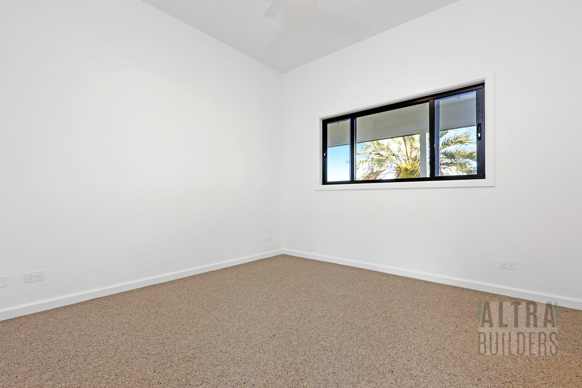 An empty room with a window and a sign that says alta builders