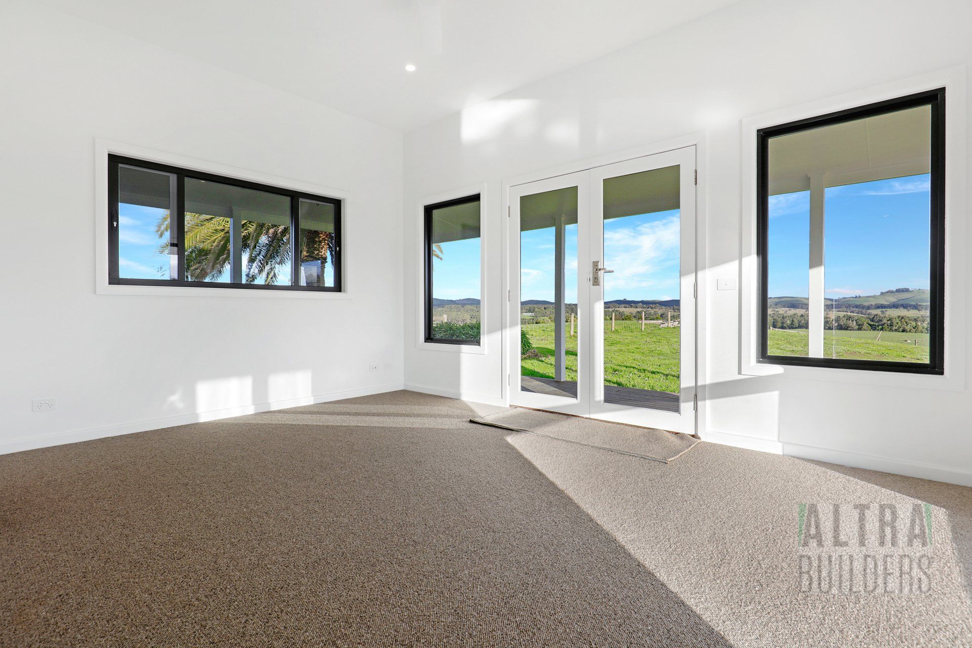 An empty room with a lot of windows and a carpeted floor.