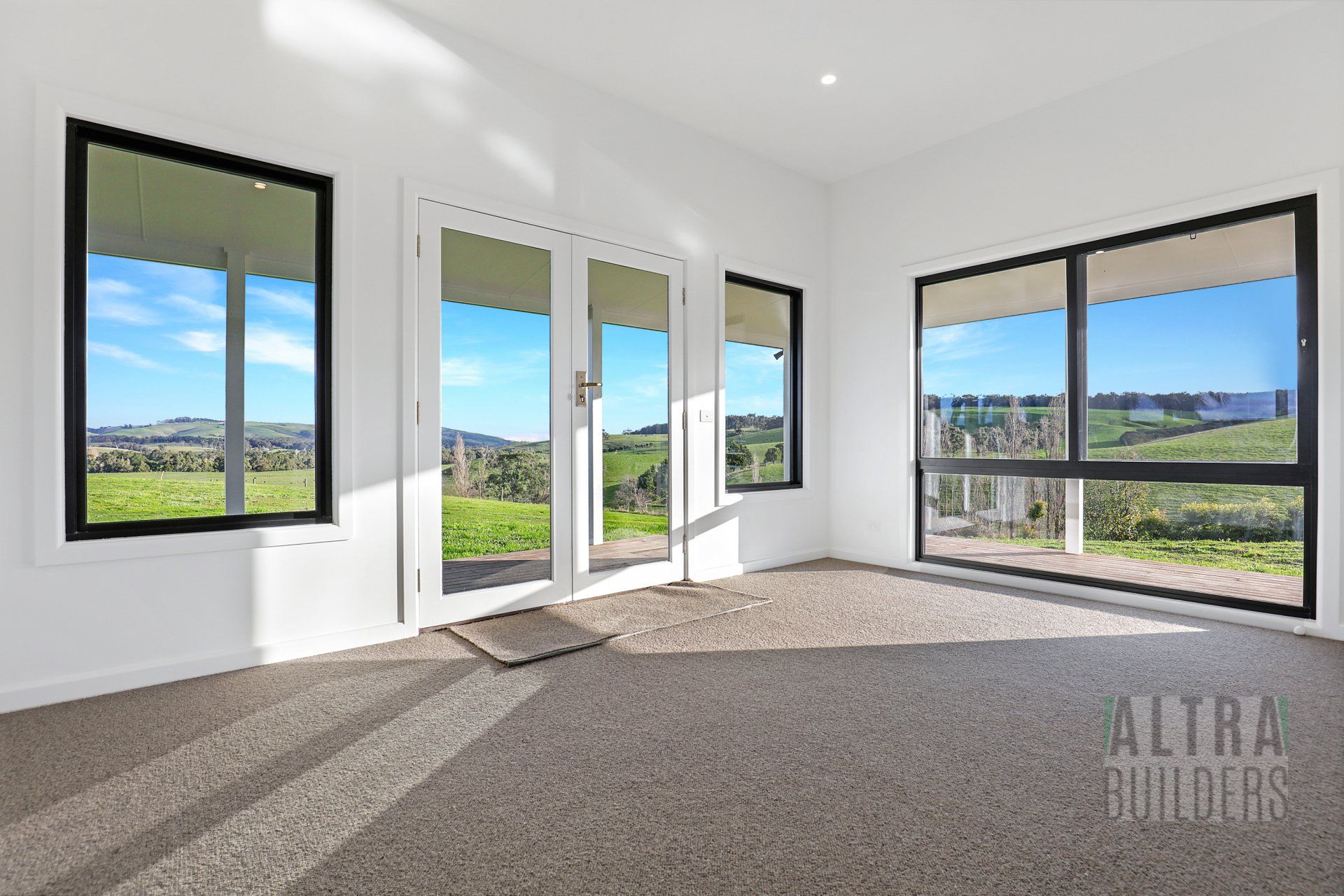 An empty room with a lot of windows and a sign that says altra builders