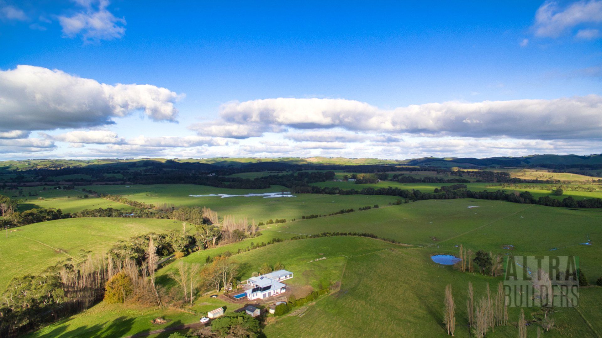 An aerial view of a lush green field with a house in the middle of it.