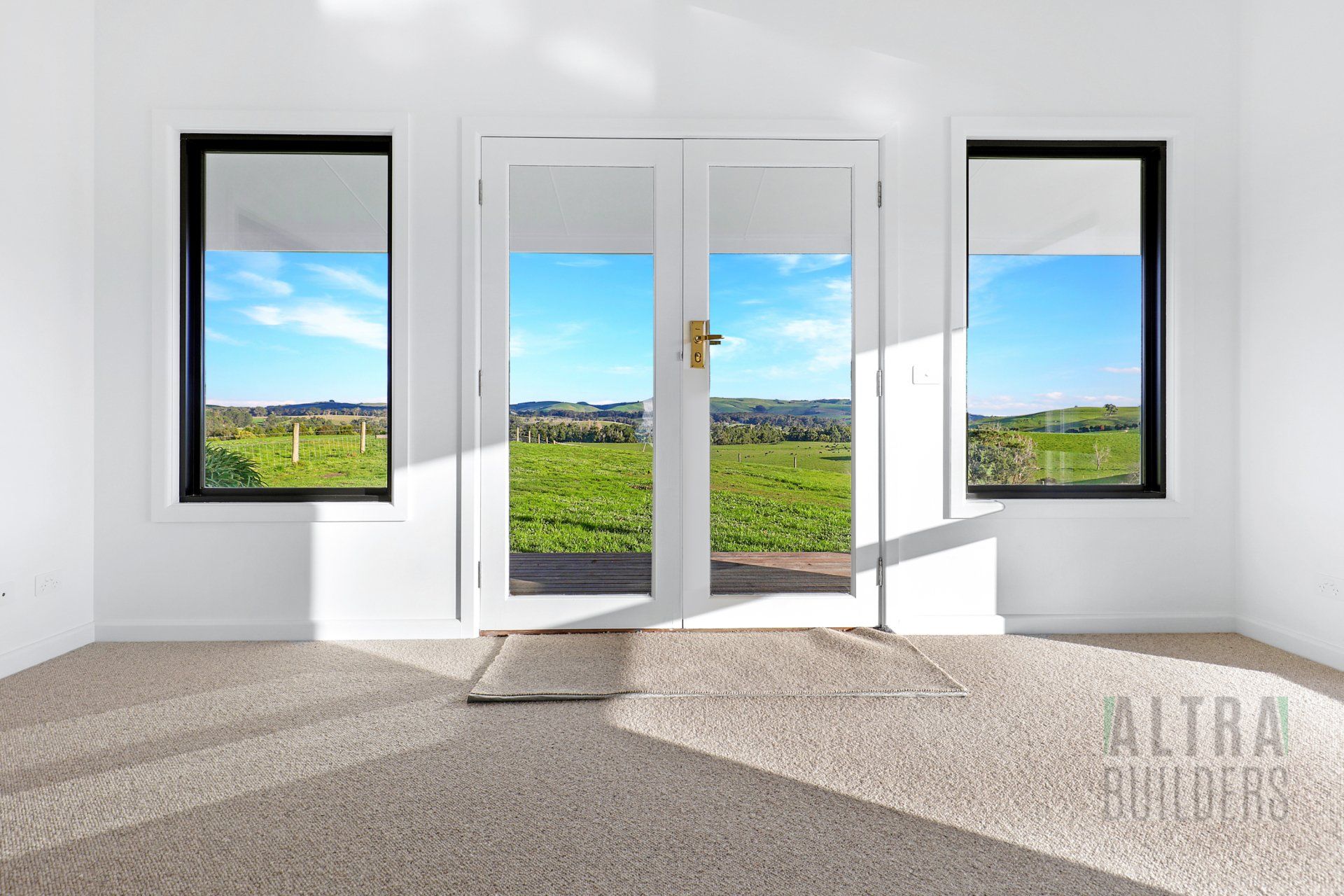An empty room with a view of a field through the windows.