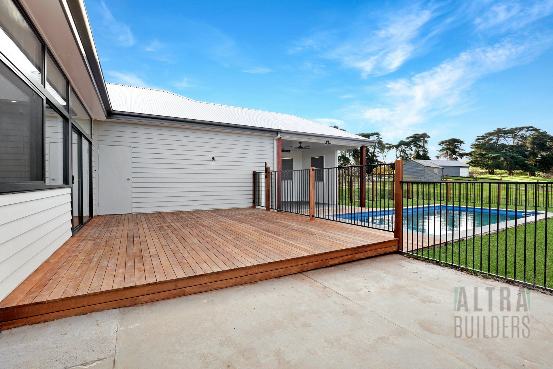 A house with a wooden deck and a fence that says altra builders