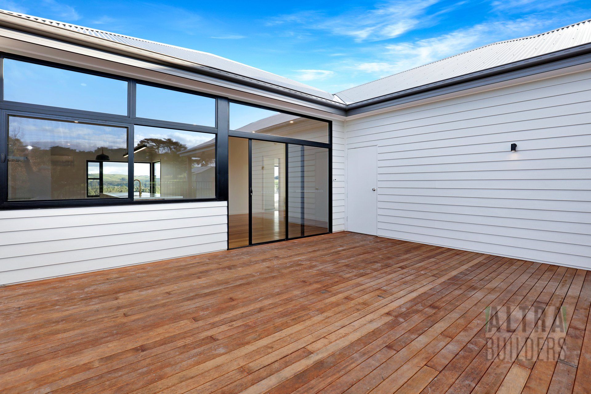 An empty deck in front of a house with sliding glass doors